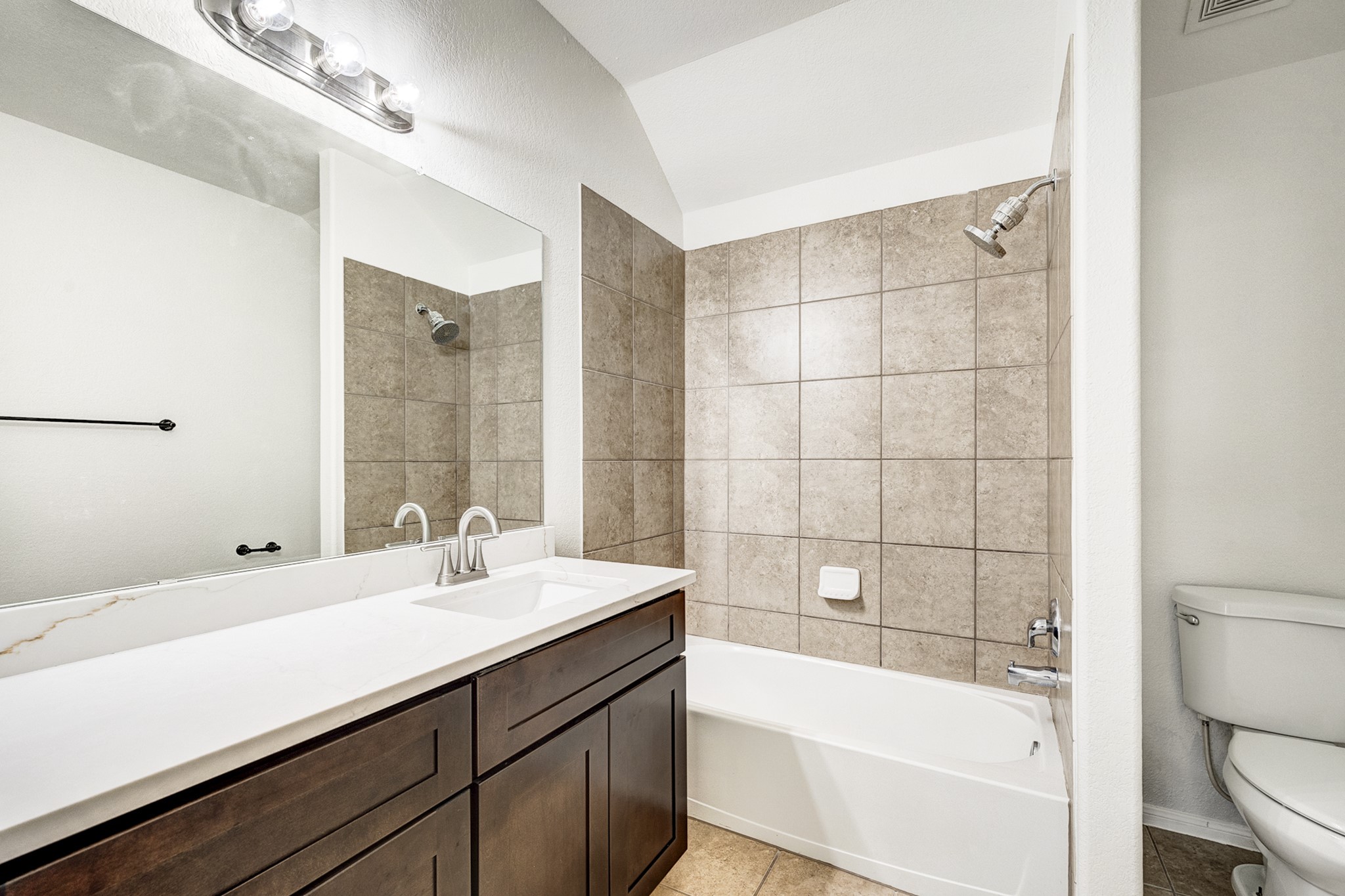 Elegant bathroom featuring a sleek vanity with dual sinks, a tiled shower-tub combo, and modern fixtures for a contemporary feel.