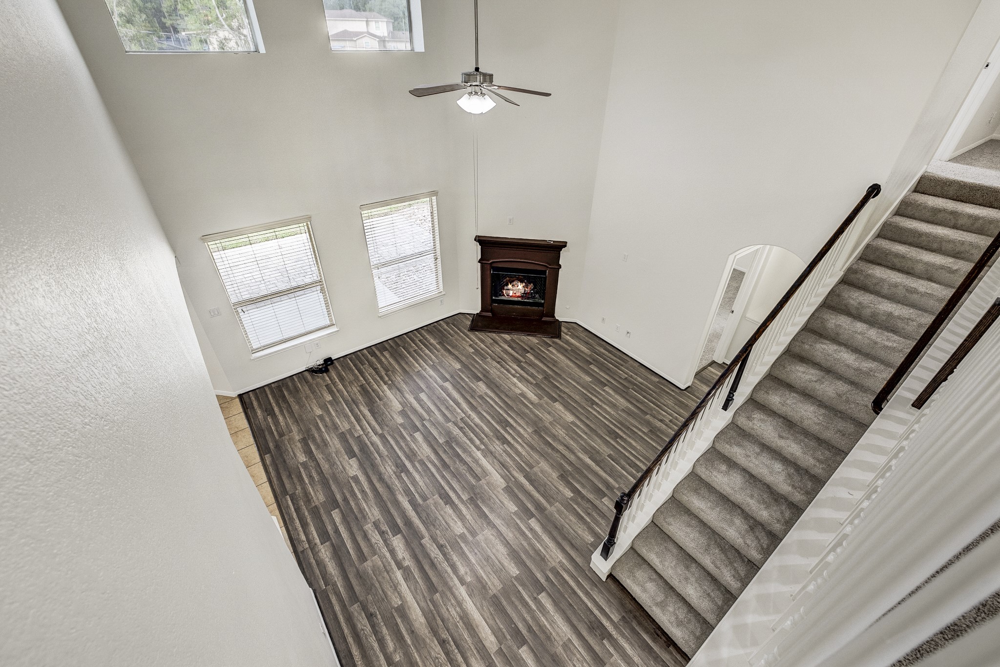 Spacious living room with soaring ceilings, a cozy fireplace, and elegant wood flooring, complemented by abundant natural light from large windows.