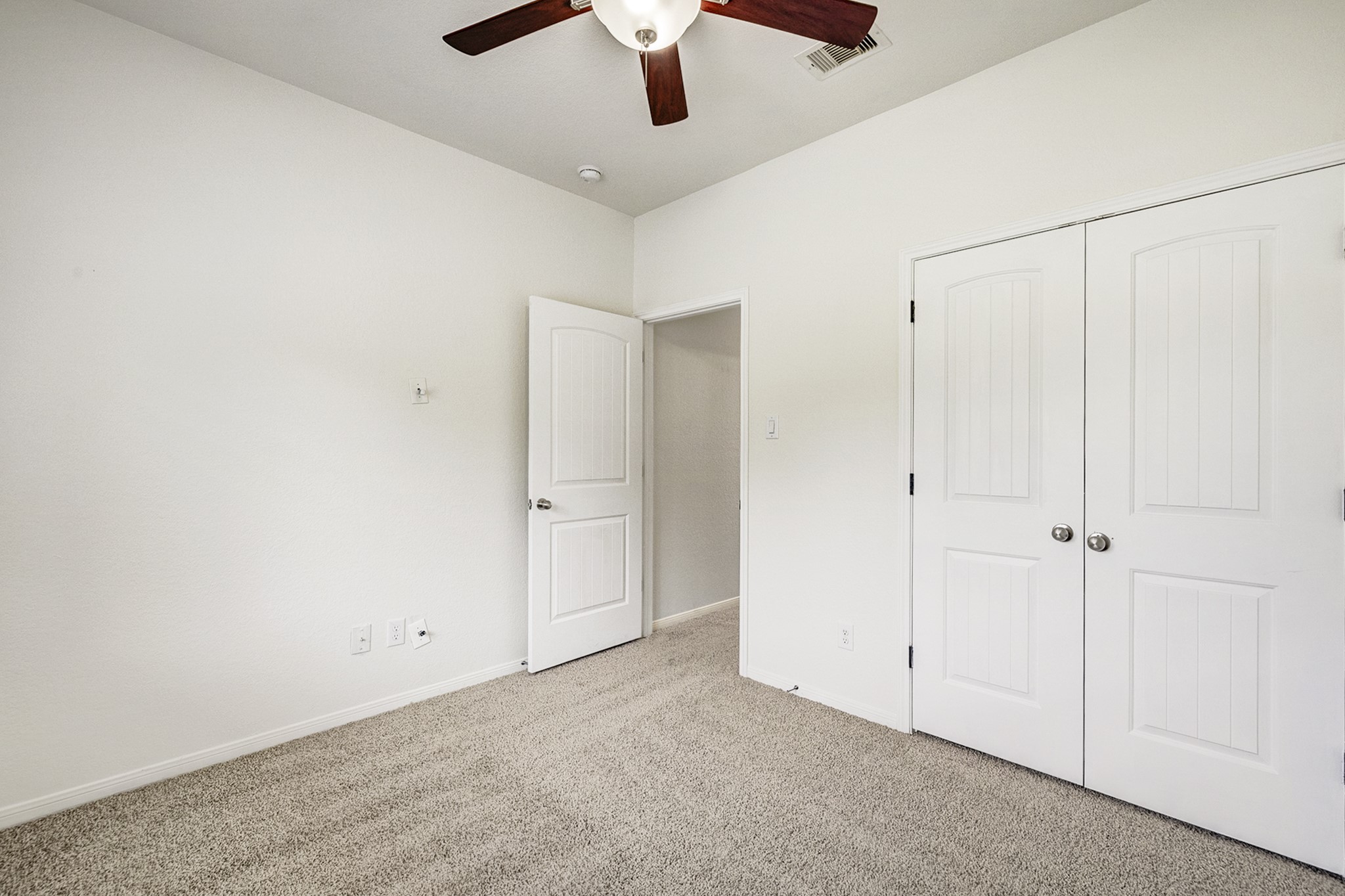 Bright and cozy bedroom featuring plush carpeting, a ceiling fan, and ample closet space with double doors.