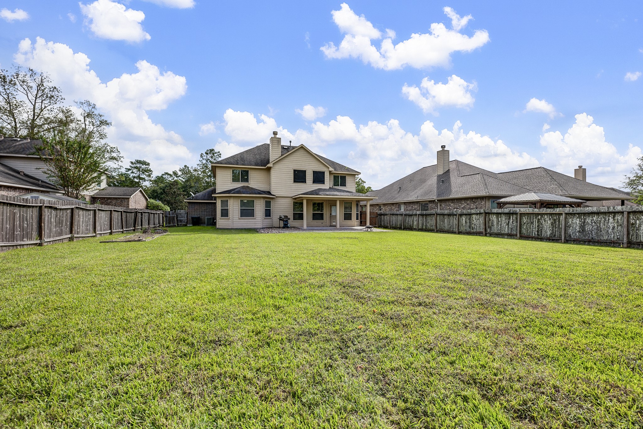 Expansive backyard with lush green lawn, perfect for outdoor activities and entertaining, complemented by a charming two-story home.