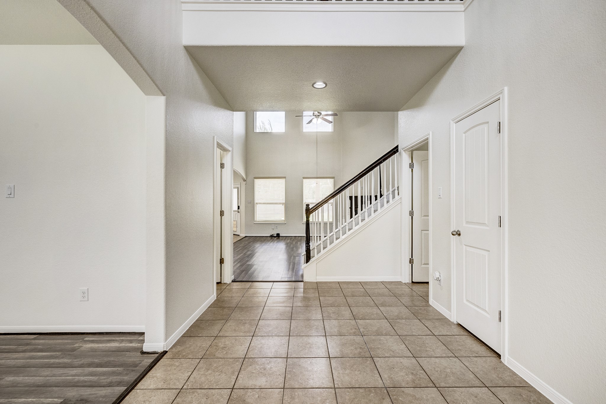 Spacious entryway featuring sleek tile flooring, high ceilings, and a modern staircase leading to the second floor.