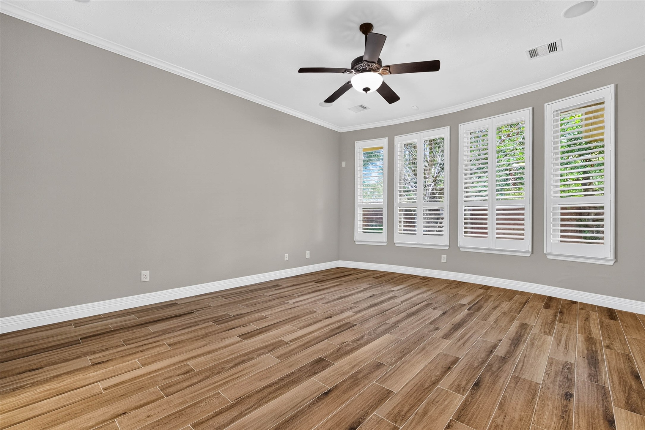 Primary bedroom featuring four large windows, a ceiling fan, and ample space for furniture