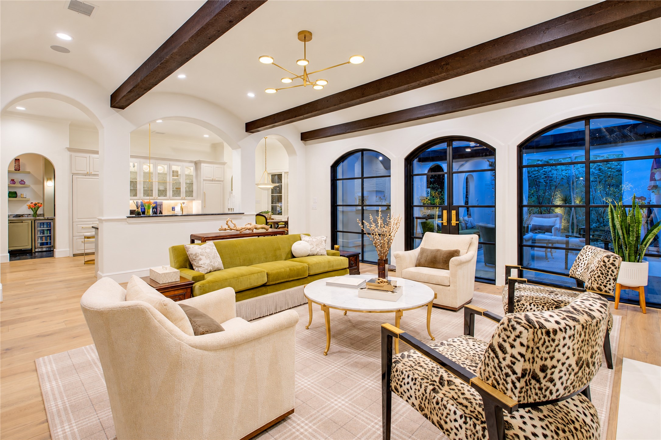 Exposed wood beams accentuate the 10-foot triple barrel-vault ceiling, while custom steel doors open to the rear patio and yard.