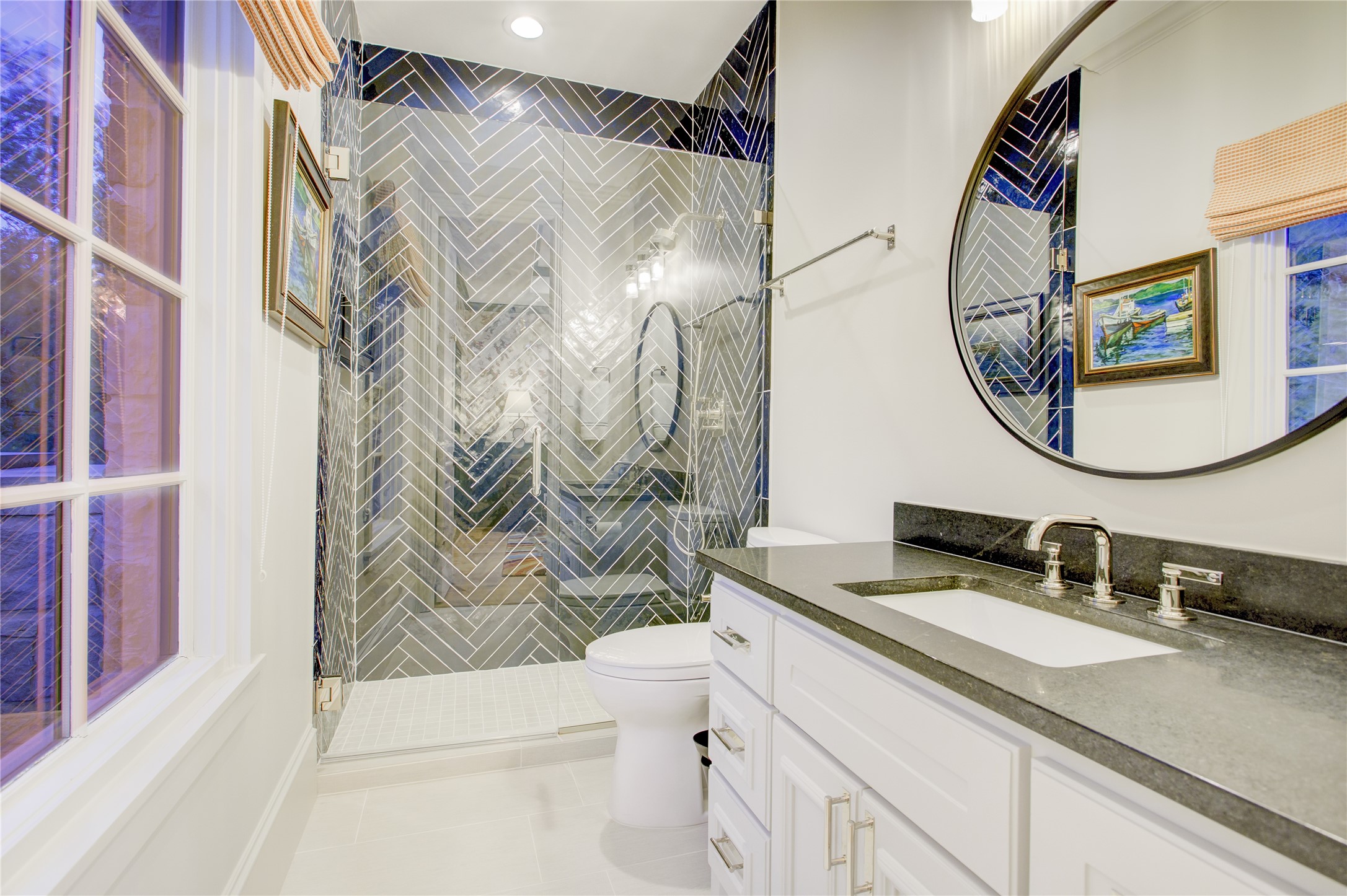 Floor-to-ceiling navy herringbone tile, a frameless glass shower, and honed black granite define this sophisticated ensuite.