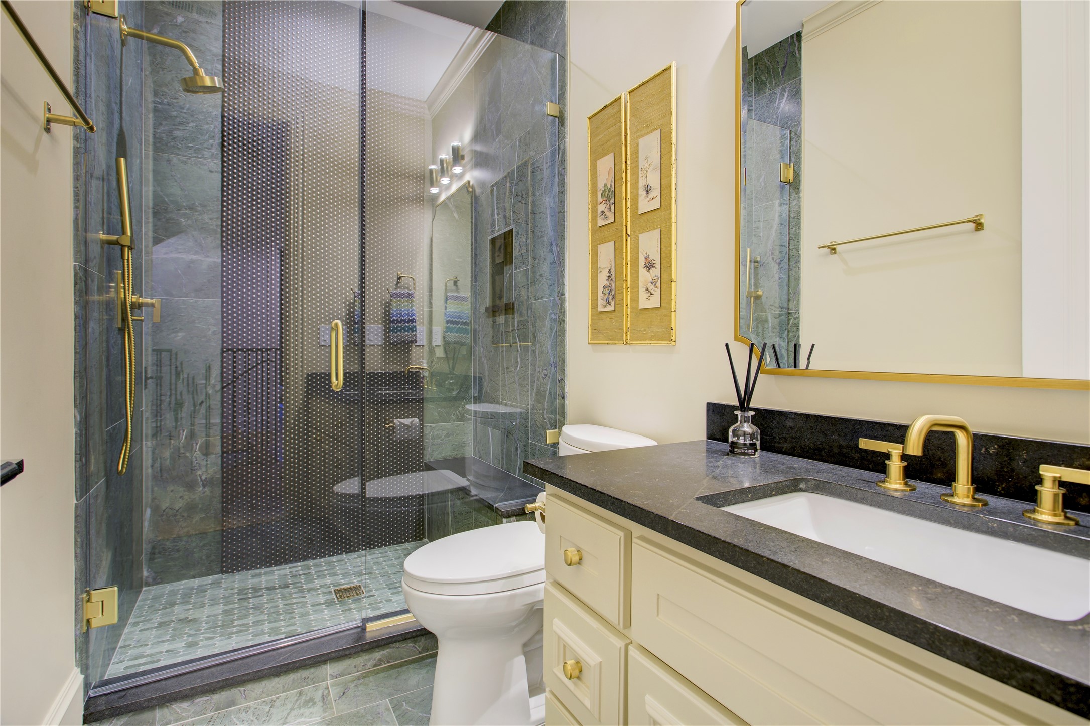 Floor-to-ceiling green stone tile pairs with black bubble accents and honed black granite countertops for a bold, sophisticated bath.