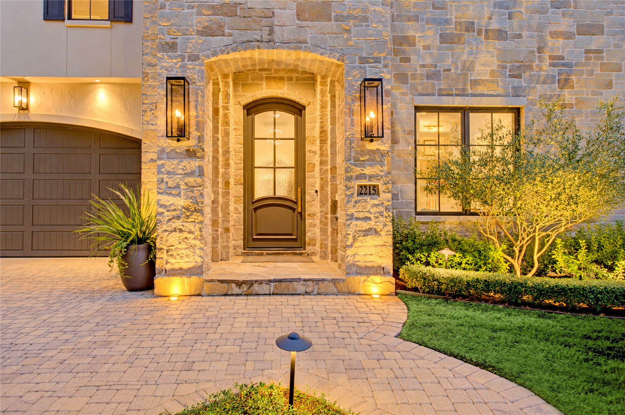 A covered stone entry welcomes guests through an eight-foot painted wood door with textured glass for added privacy.