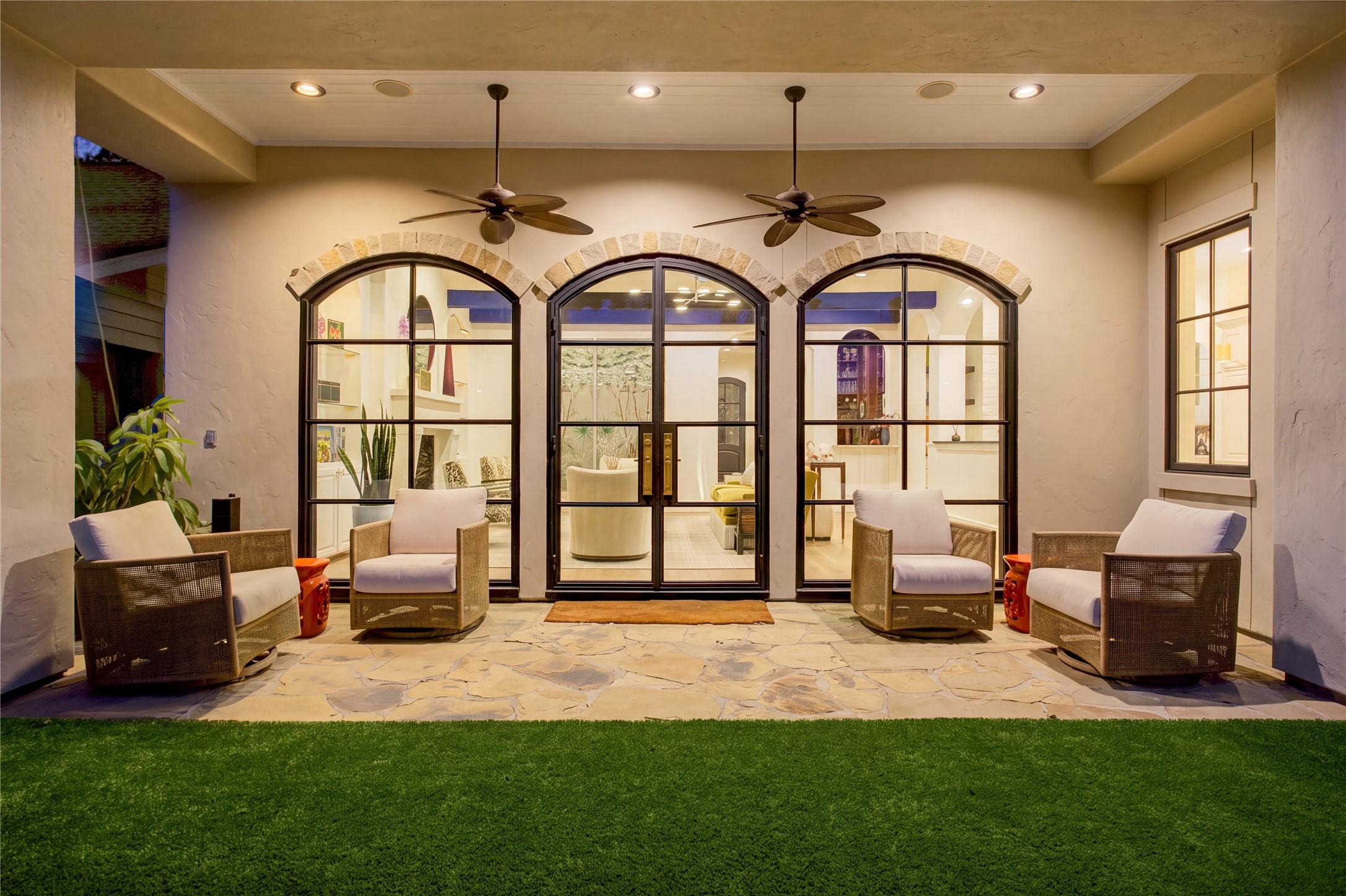Refined outdoor living with natural flagstone, a classic beadboard ceiling, dual ceiling fans, and lush premium turf.