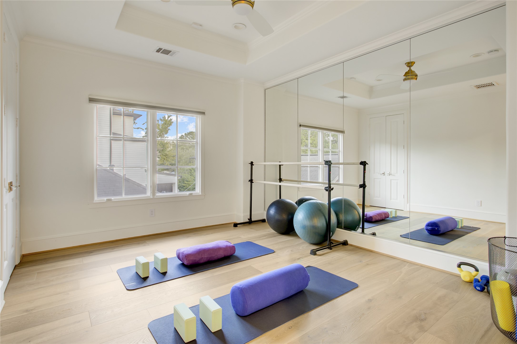 Wide-plank white oak floors and a 10-foot tray ceiling frame this flexible fourth bedroom, currently styled as a mirrored fitness studio.