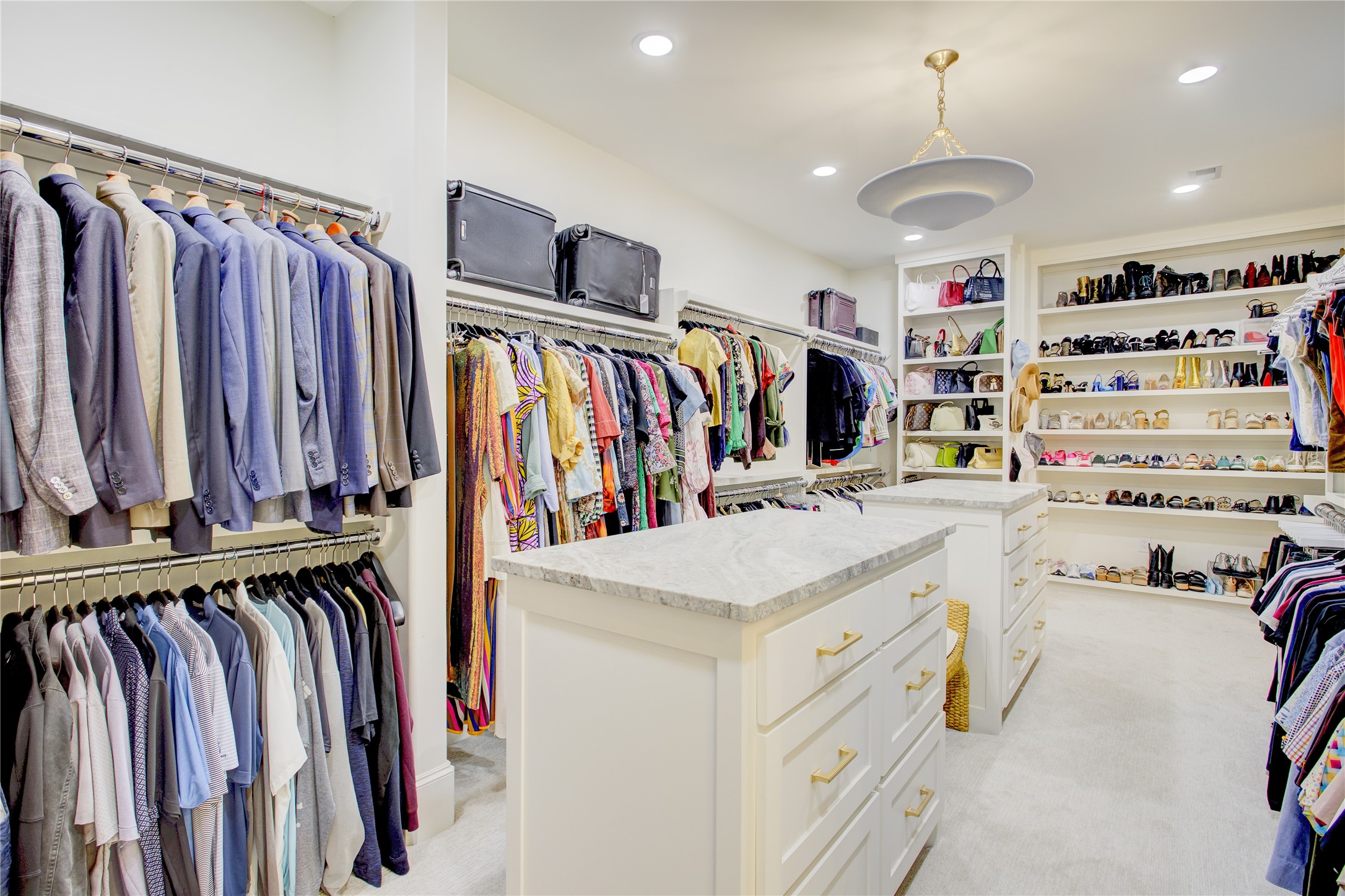 Designed like a private boutique, this primary closet features custom built-ins and dual dolomite-topped packing islands.