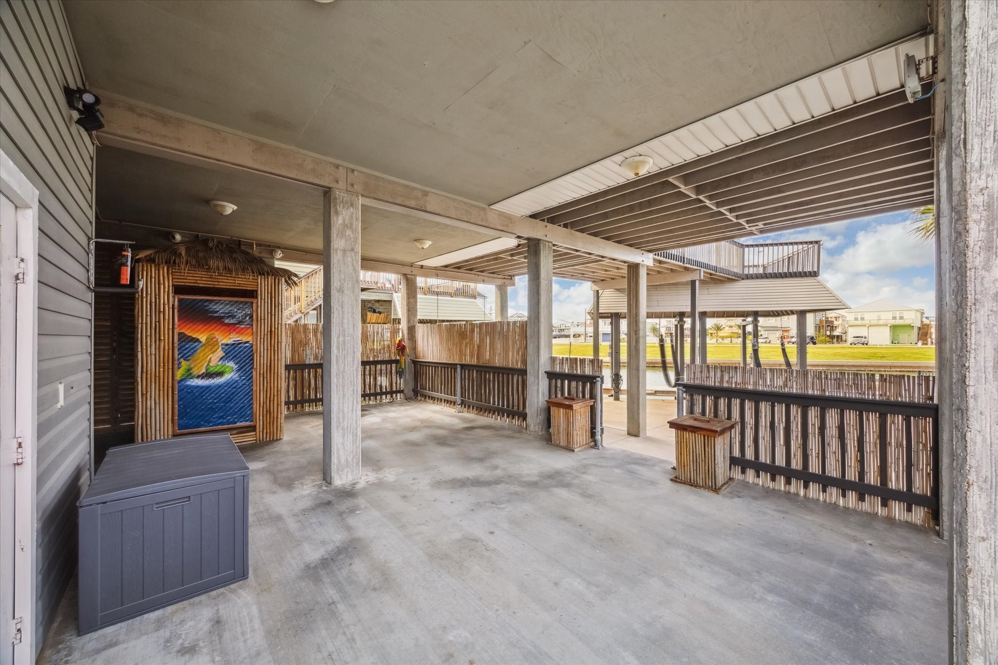 Spacious covered patio area with concrete flooring, ideal for outdoor gatherings. It features a unique tiki-style structure 9 your ground level 1/2 bath) . The patio overlooks the pool  creating a relaxed, tropical atmosphere.