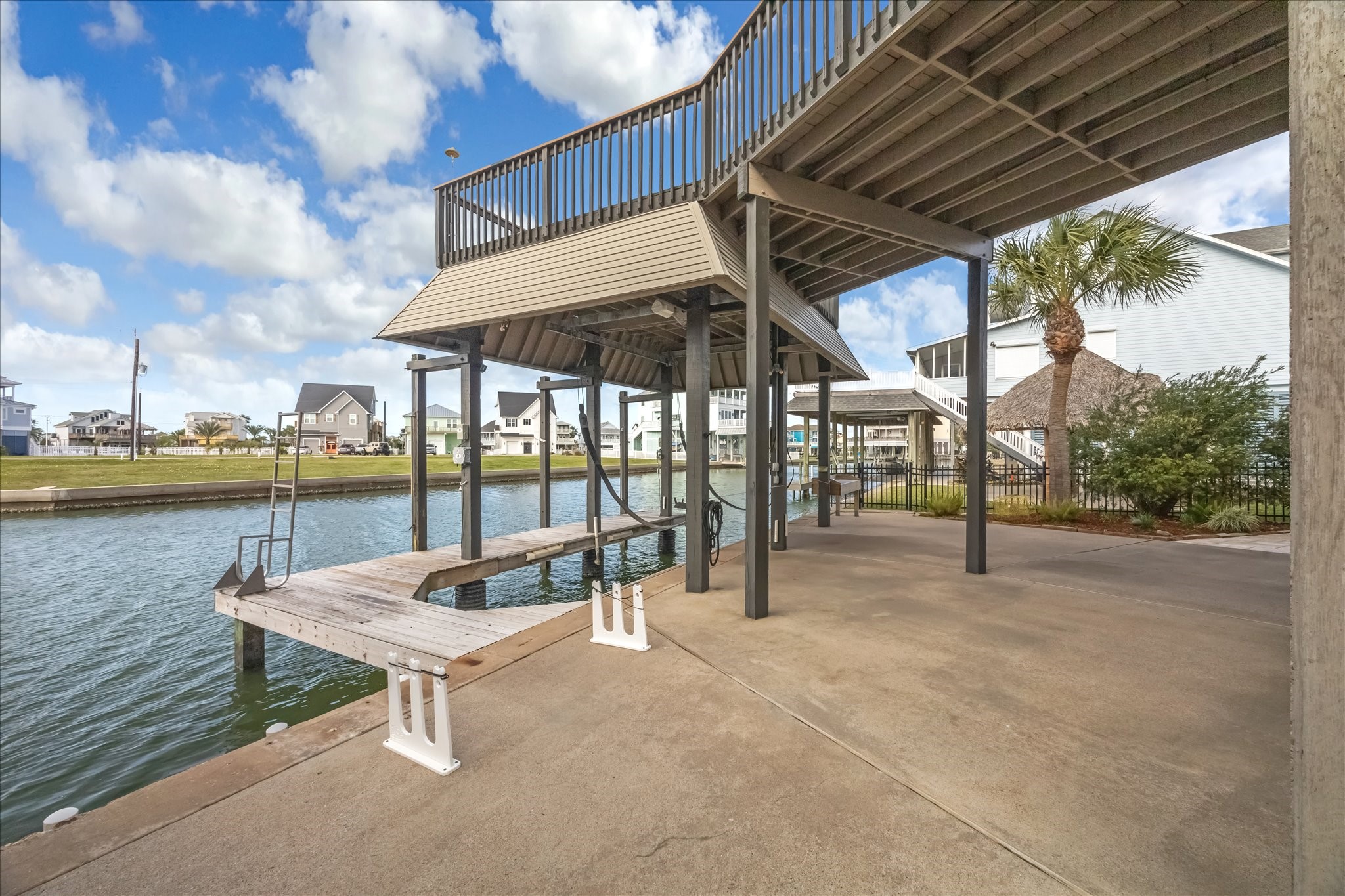 With your own  private dock and boat lift, you have direct canal access. The area is well-maintained, with a spacious concrete patio, palm tree, and a view of neighboring homes, perfect for boating enthusiasts.
