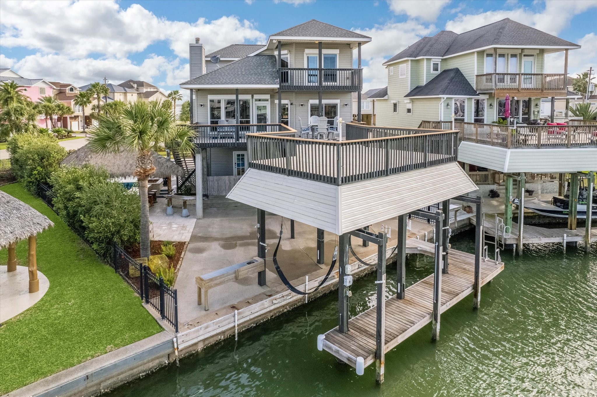 This Tiki Island waterfront home features a spacious deck with stunning views, a boat lift, and a covered patio area. Its perfect for outdoor entertaining and enjoying the serene canal access.