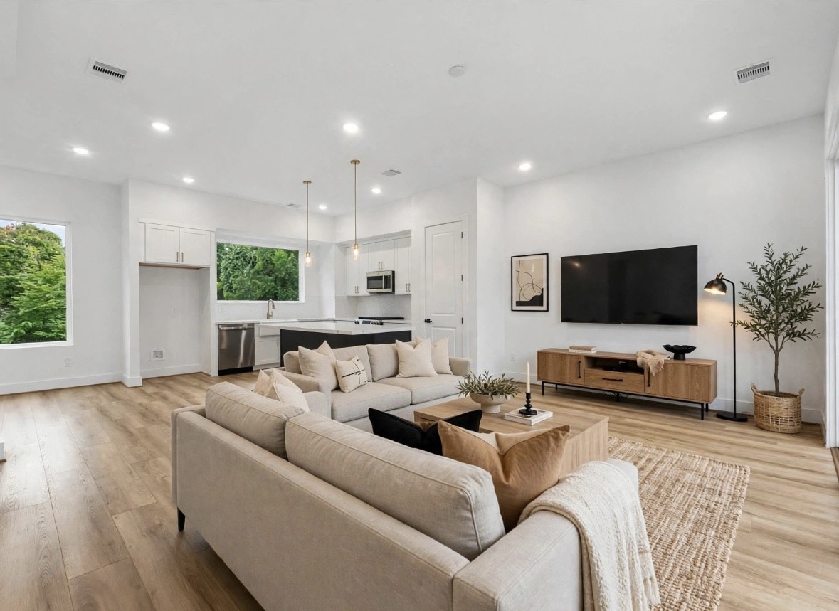 Spacious living area with an open-concept layout connecting seamlessly to the kitchen and dining space. Sliding glass doors open to the balcony, bringing in plenty of natural light, while a convenient half bath is located just across the hall.