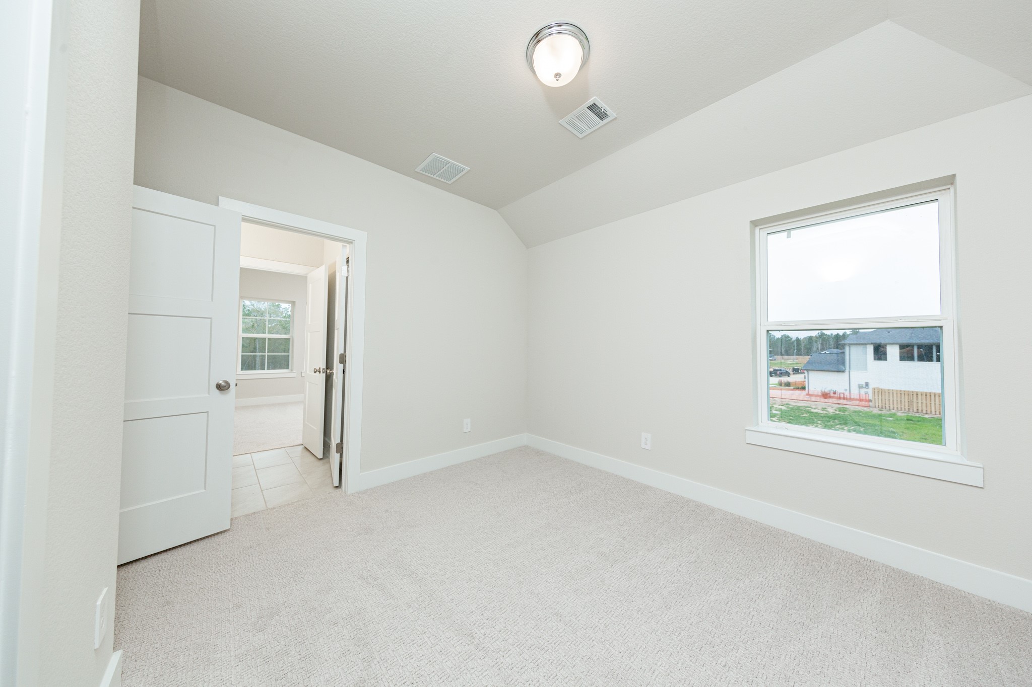 This inviting secondary bedroom combines comfort and modern elegance, featuring plush carpeting, a neutral color palette, and abundant natural light streaming through a large window. Discover the efficiency and convenience of accessing the secondary bathroom with another secondary bedroom--a highly functional solution for busy families.
