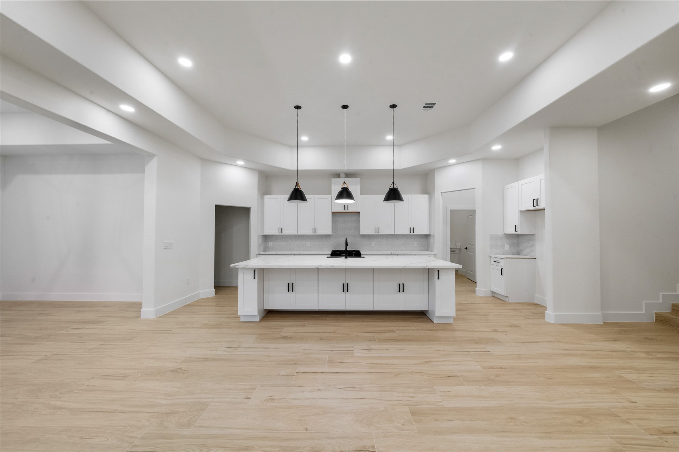 Beautifully designed kitchen serves as the centerpiece of the home, showcasing an oversized island, custom cabinetry, and sophisticated pendant lighting. The open layout creates a seamless connection to the spacious living and dining areas.