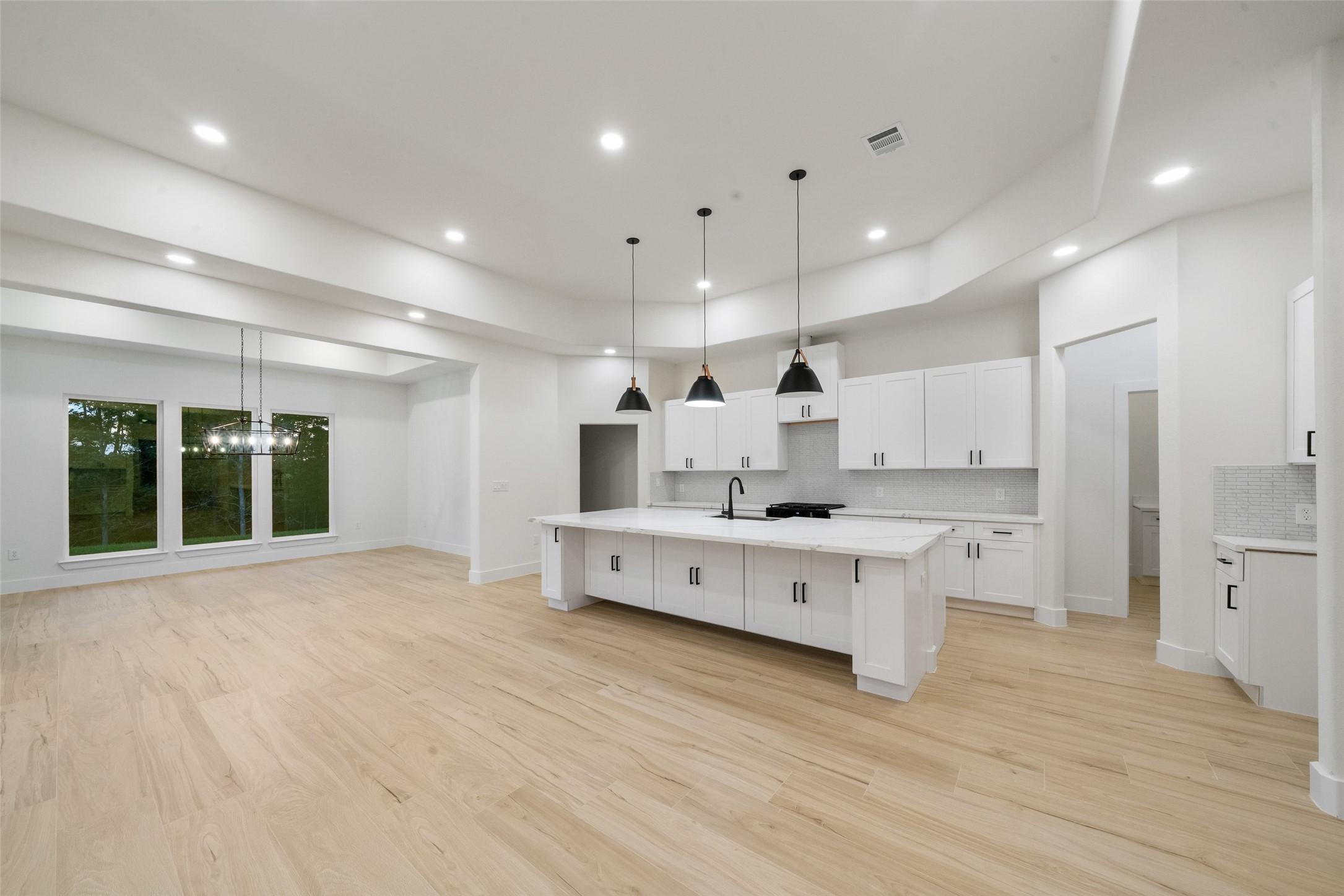 Expansive living and dining spaces beautifully complement the gourmet kitchen, creating a sophisticated setting for everyday living and entertaining. Large windows invite natural light while highlighting the home's elegant finishes and thoughtful design.