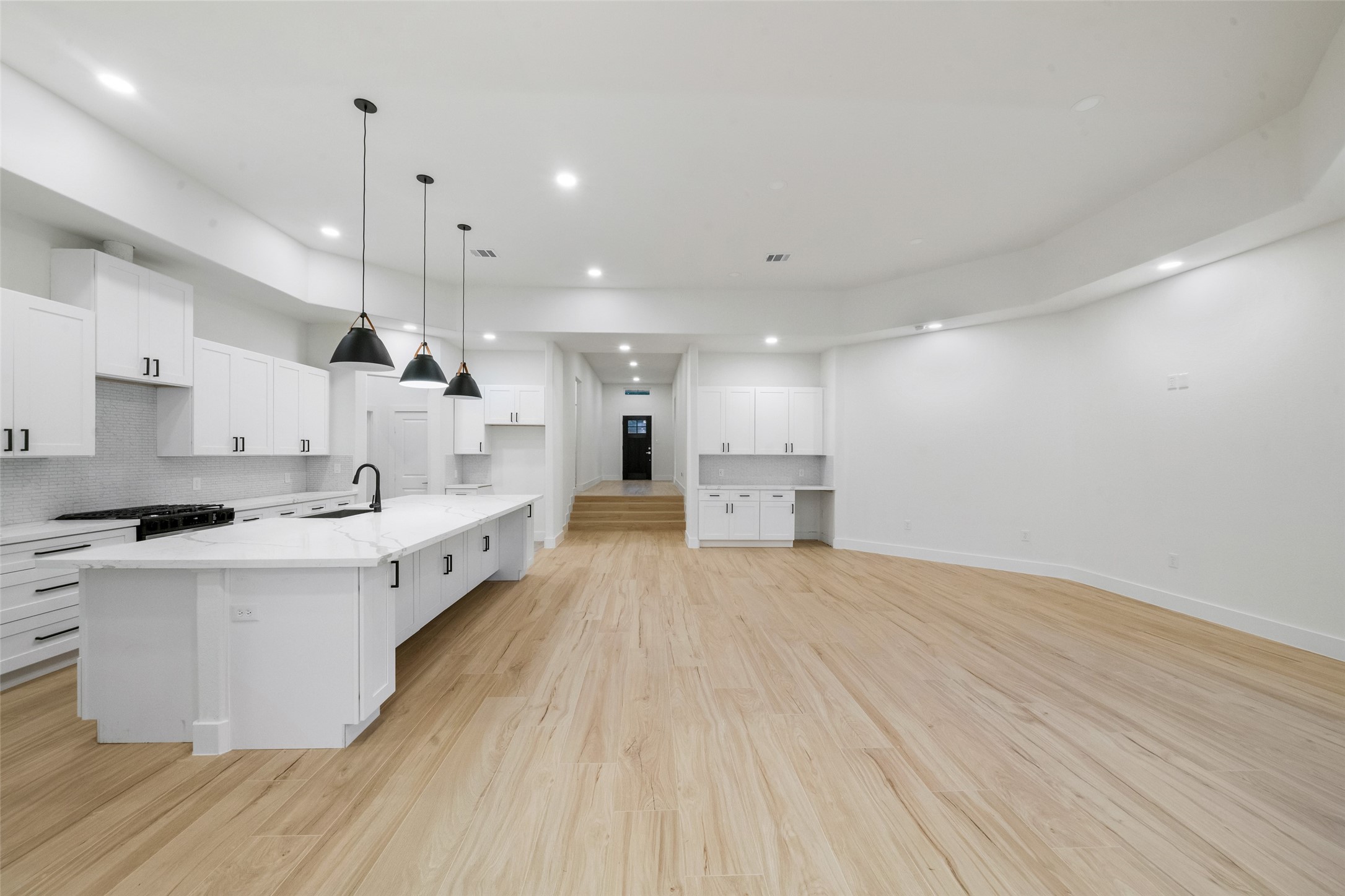 Impressive open-concept design seamlessly connects the gourmet kitchen and expansive living area. Beautiful wood-look flooring, recessed lighting, and elegant architectural details create an inviting atmosphere ideal for entertaining.