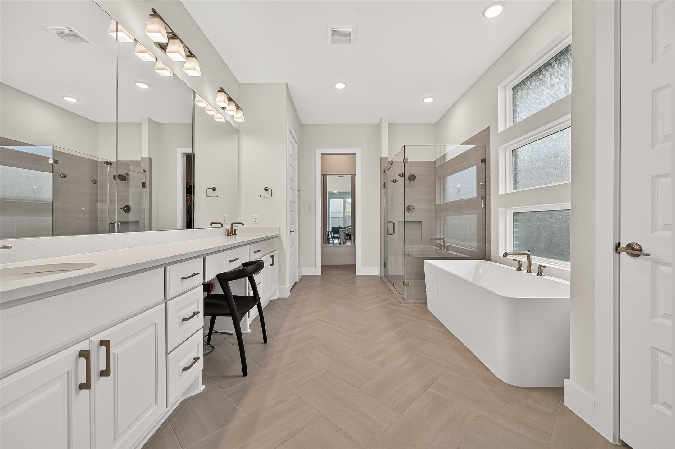The primary bath offers double vanities, abundant countertop and storage space, a huge soaking tub, an oversized glass-enclosed walk-in shower with bench, and a large primary closet.