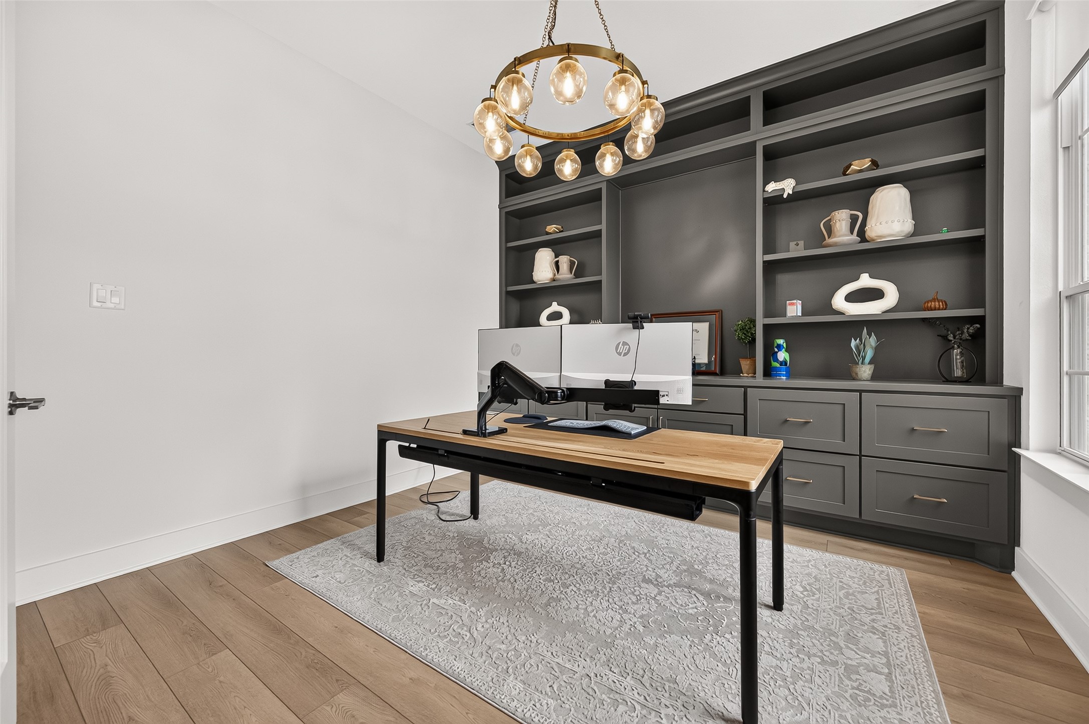 A dedicated home office enclosed by double glass doors, featuring custom built-in cabinetry.