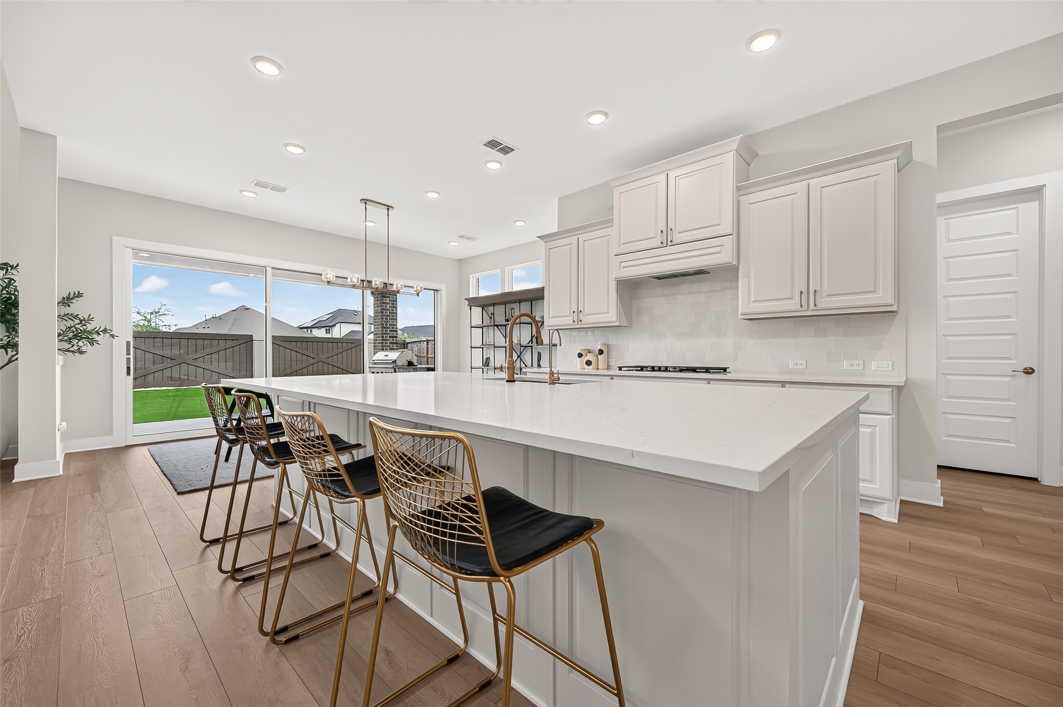 The chefs kitchen is the centerpiece of the home, featuring a massive island with manufactured stone countertops, built-in stainless-steel appliances, gas range, beautiful cabinetry with hardware, and a sink equipped with reverse osmosis.