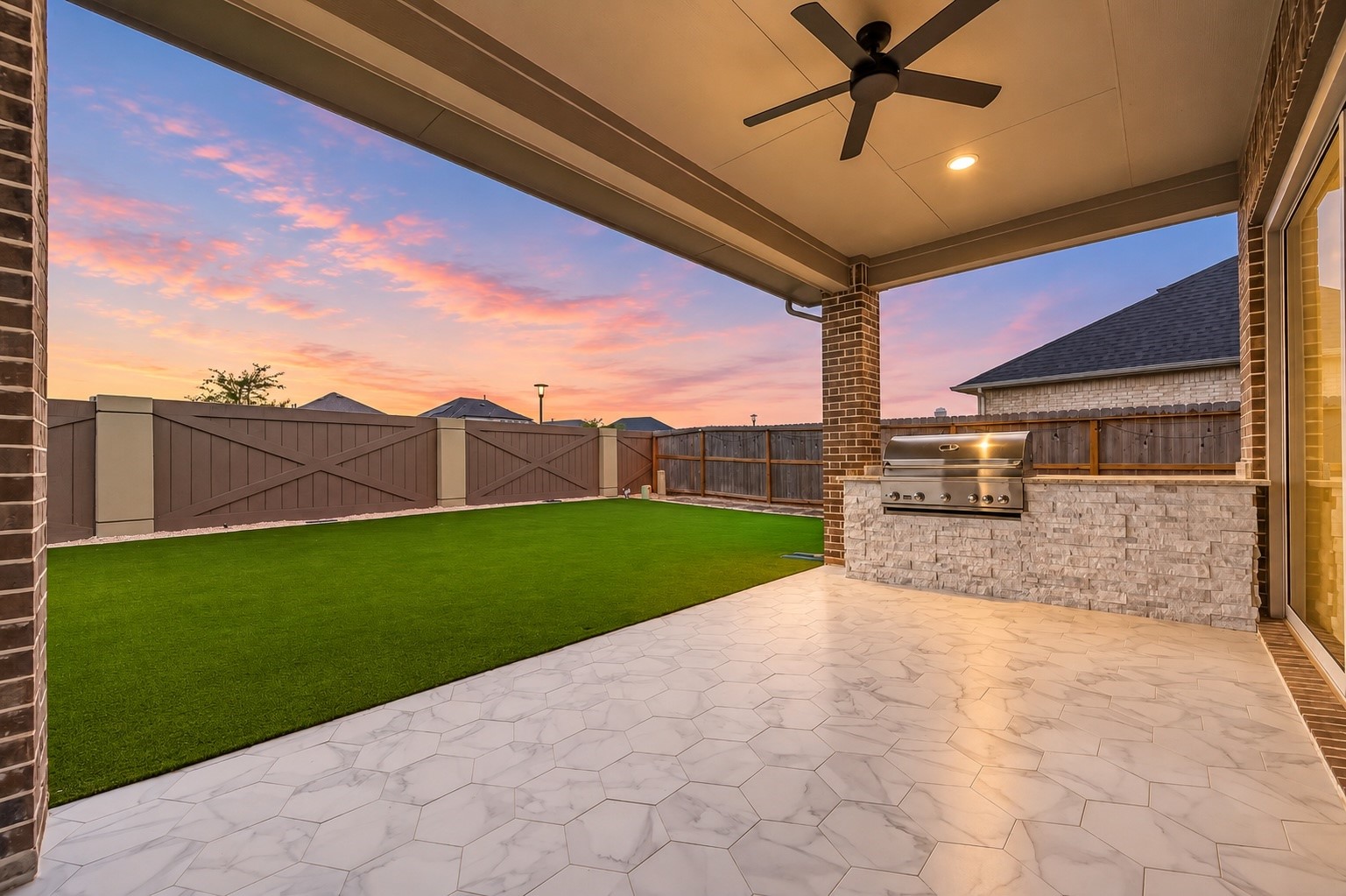 The outdoor living space is equally impressive, featuring a large covered patio with tiled pavers, outdoor kitchen, extensive seating area, fully turfed backyard, and no rear neighbors.