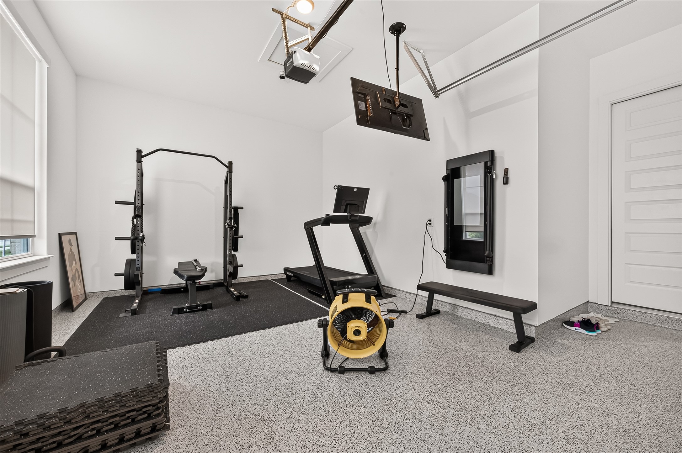 The property also a three-car garage! Shown here, additional single detached garage with its own private entrance is currently being used as a workout space and offers excellent flexibility for a gym, studio, workshop, or additional storage.