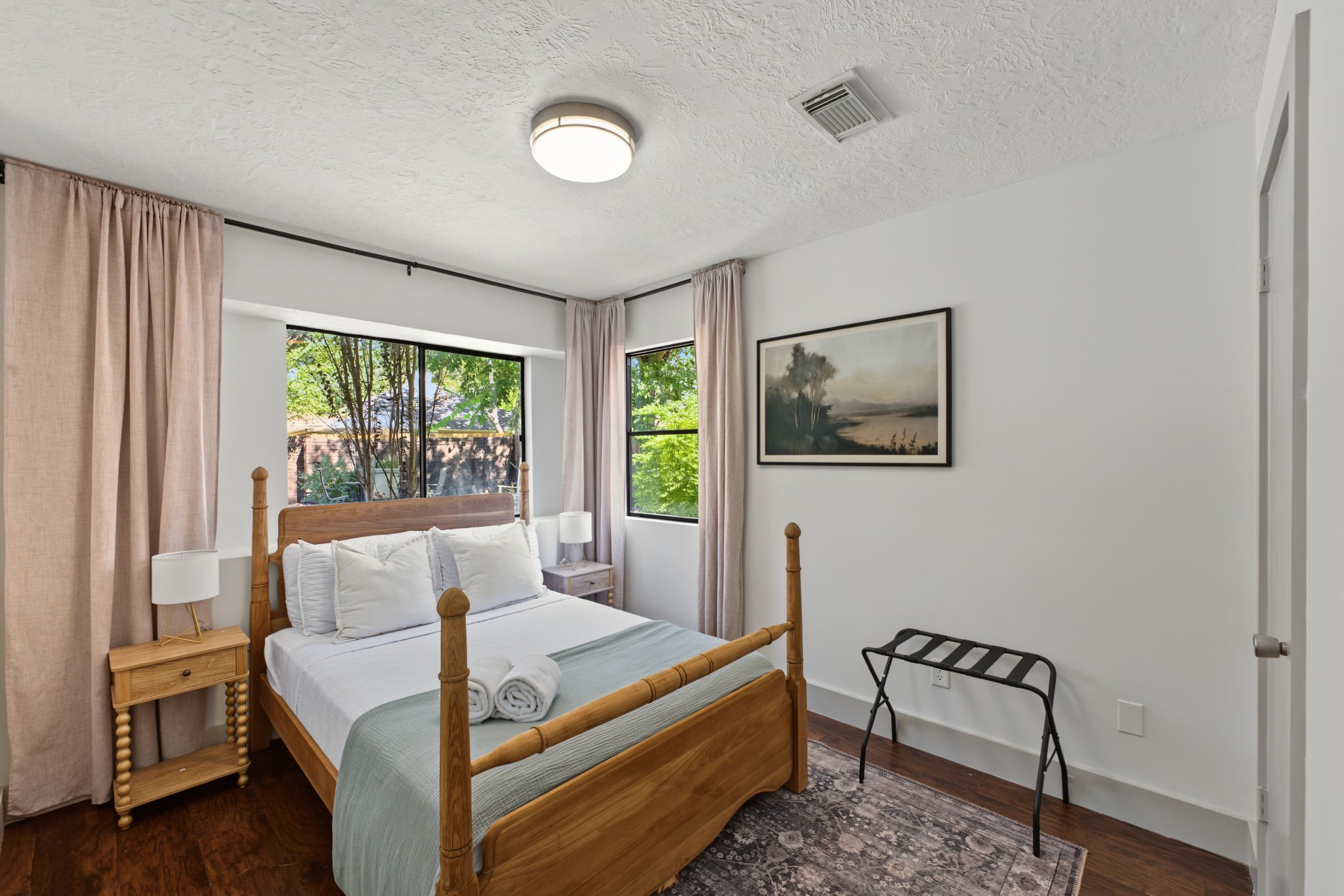 Secondary bedroom #1 features rich wood-look flooring and black-framed windows.