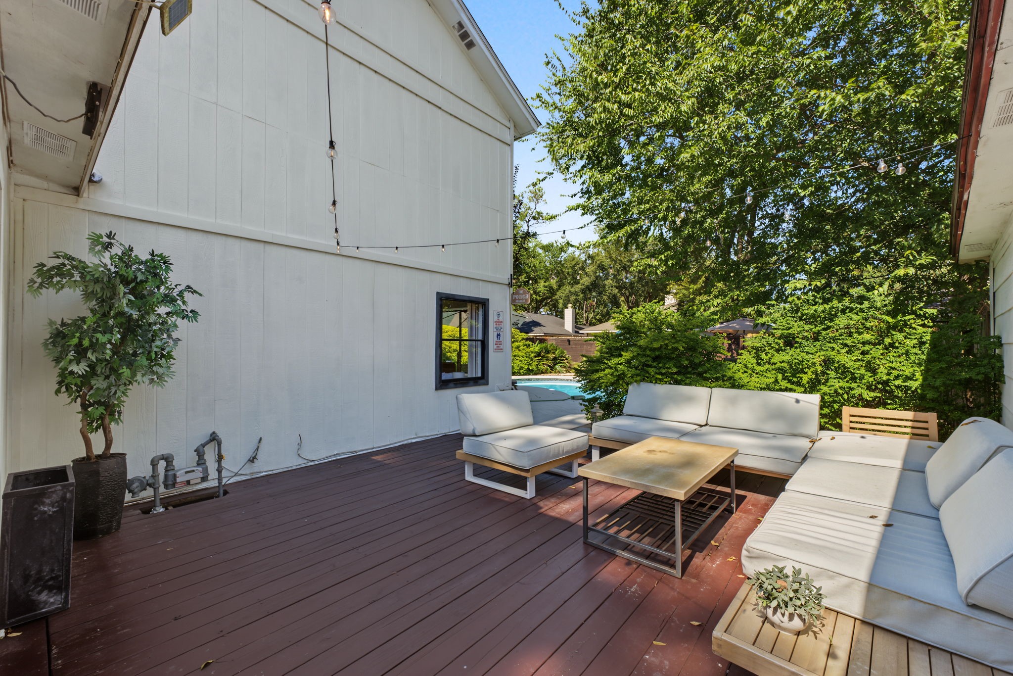 Expansive wood deck under string lights is made for entertaining poolside!
