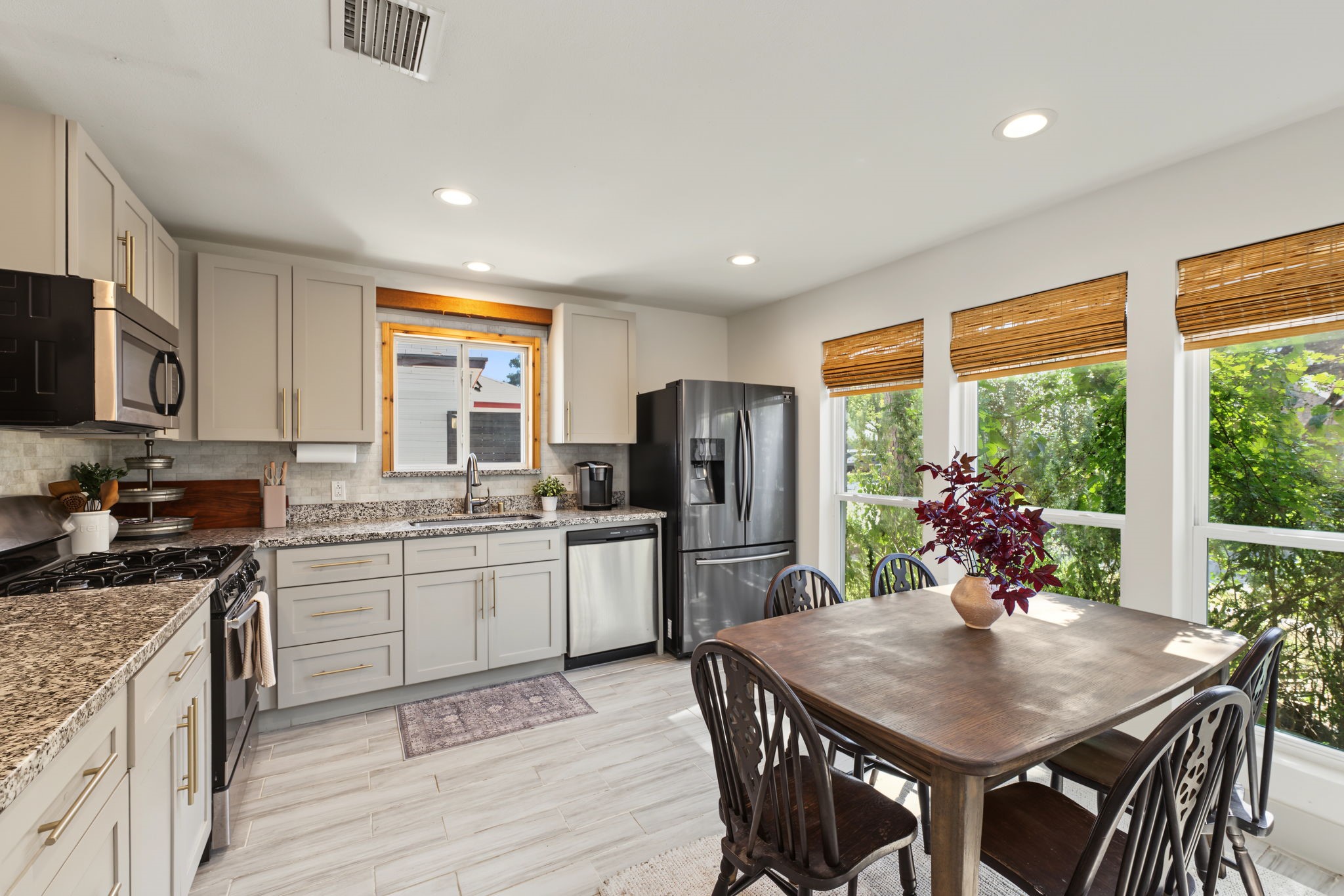 Remodeled kitchen features shaker cabinets with gold hardware, granite countertops, marble-look mosaic backsplash and stainless appliances including a gas range!