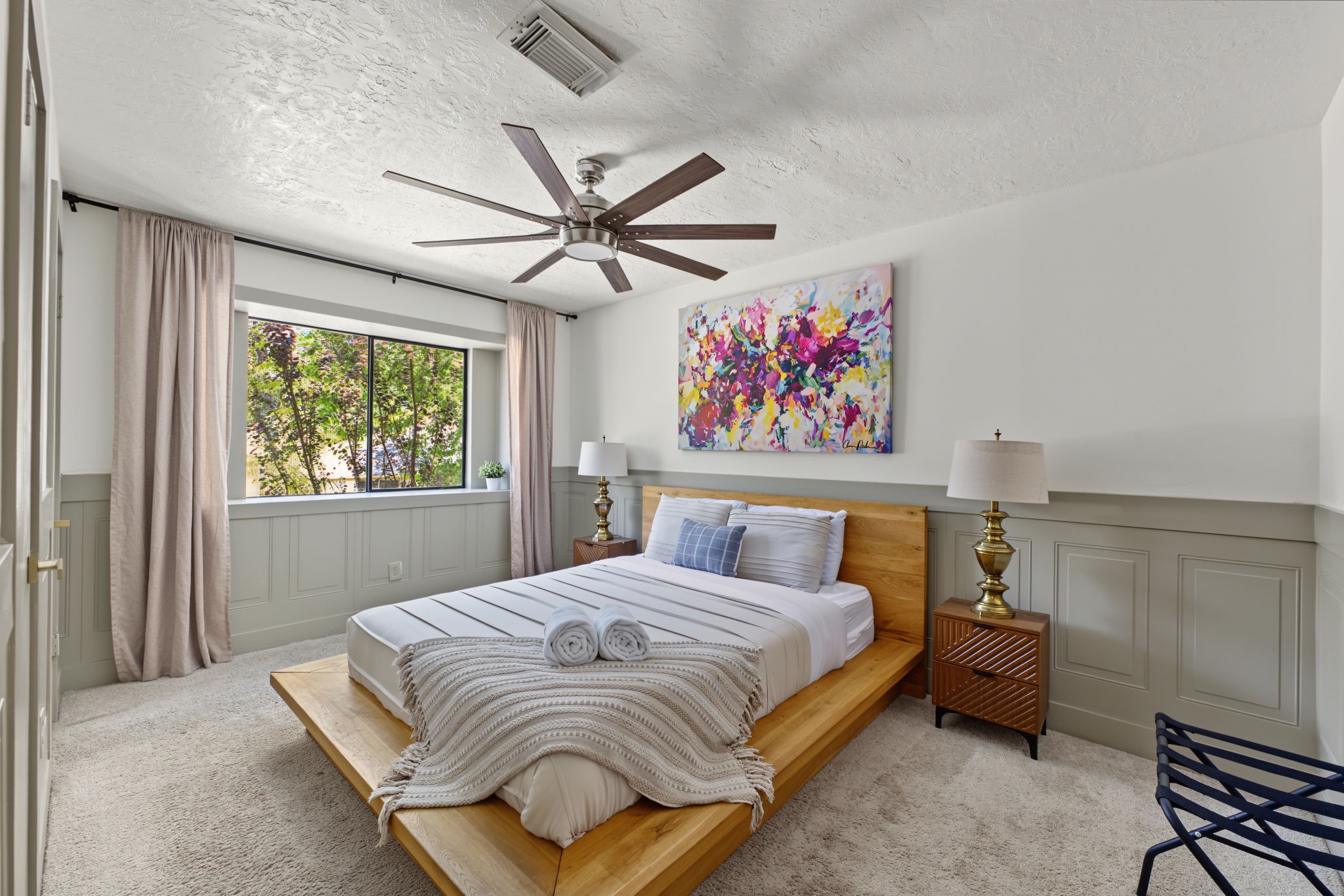 Secondary bedroom #2 features plush carpet, raised-panel wainscoting and an oversized ceiling fan.