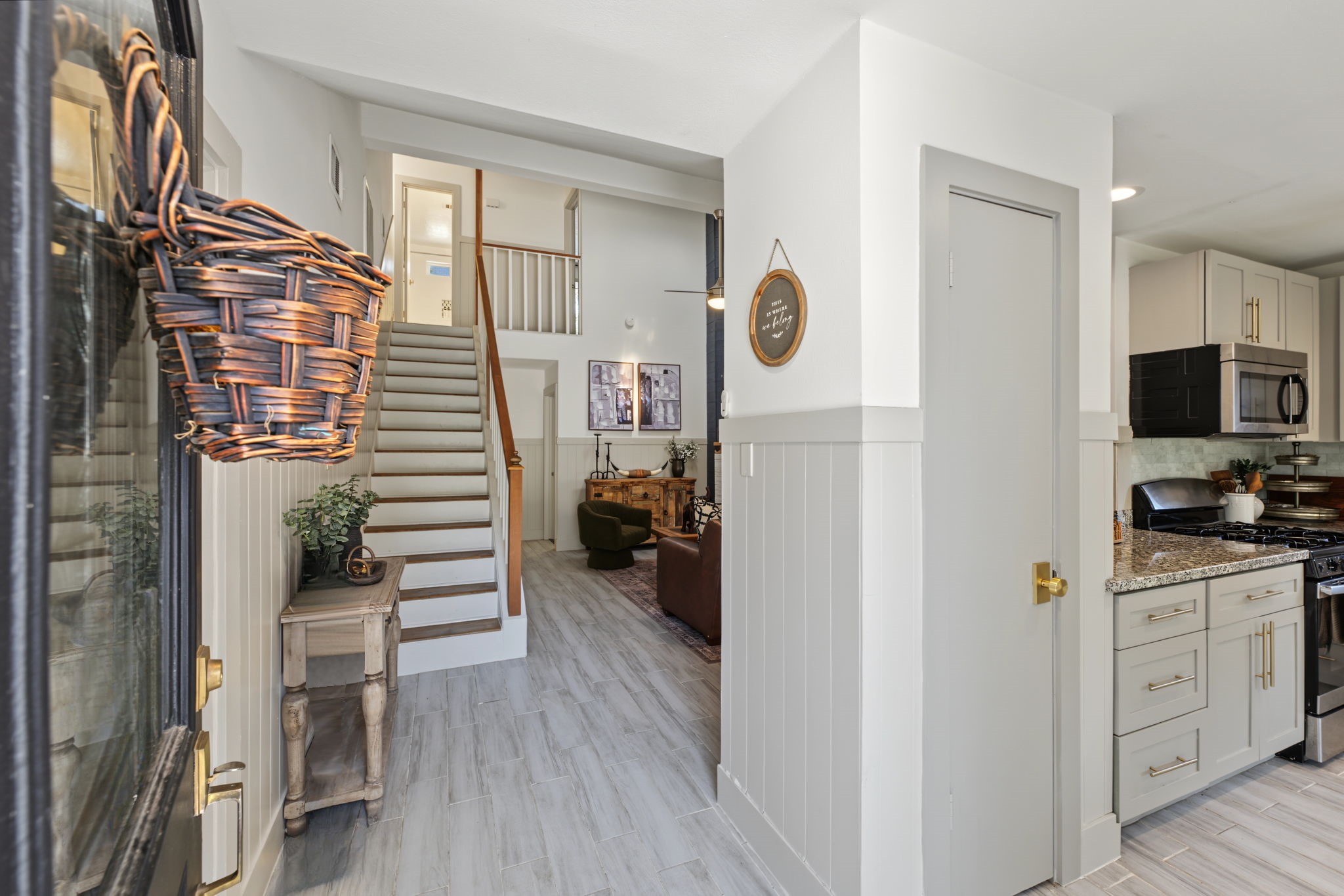 Entry opens to wood-look tile flooring, shiplap wainscoting and a peek into the kitchen.