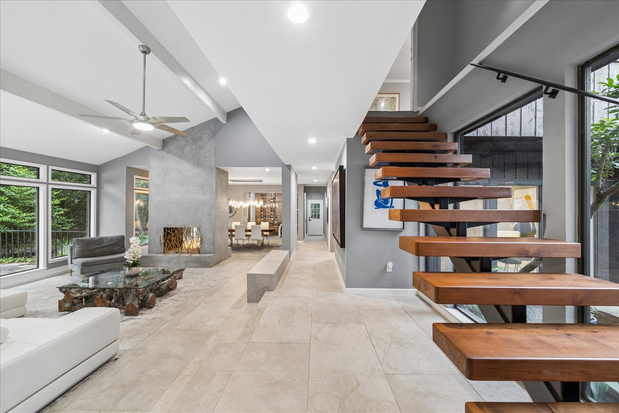 As you enter, you will find a spacious open living area with large windows, a sleek wood and metal floating staircase, and a contemporary fireplace. The neutral palette and abundant natural light create a welcoming and stylish atmosphere.