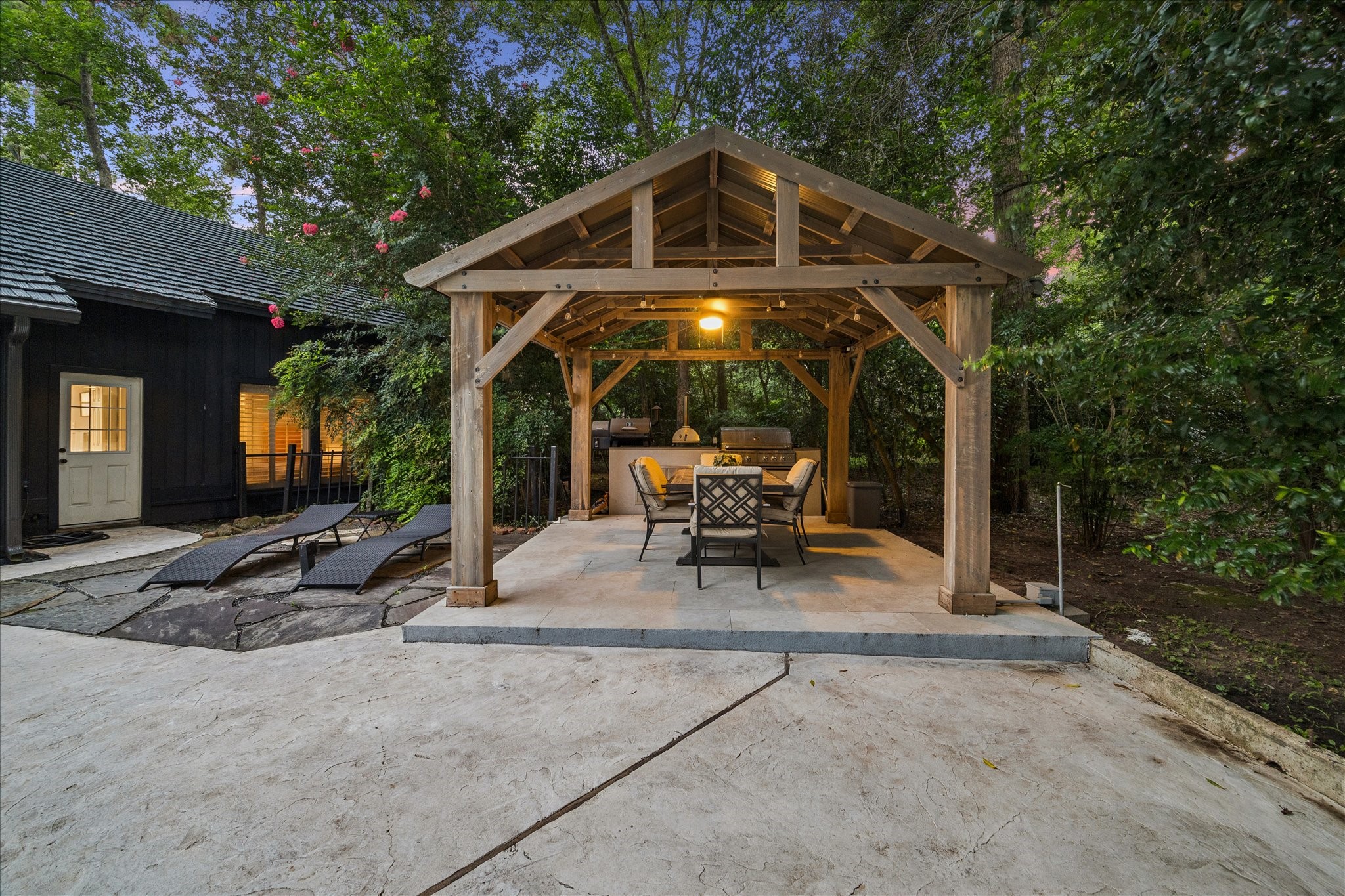 Enjoy lots of family gatherings in this serene backyard with a cozy wooden pergola, featuring outdoor seating and a dining area, ideal for entertaining.