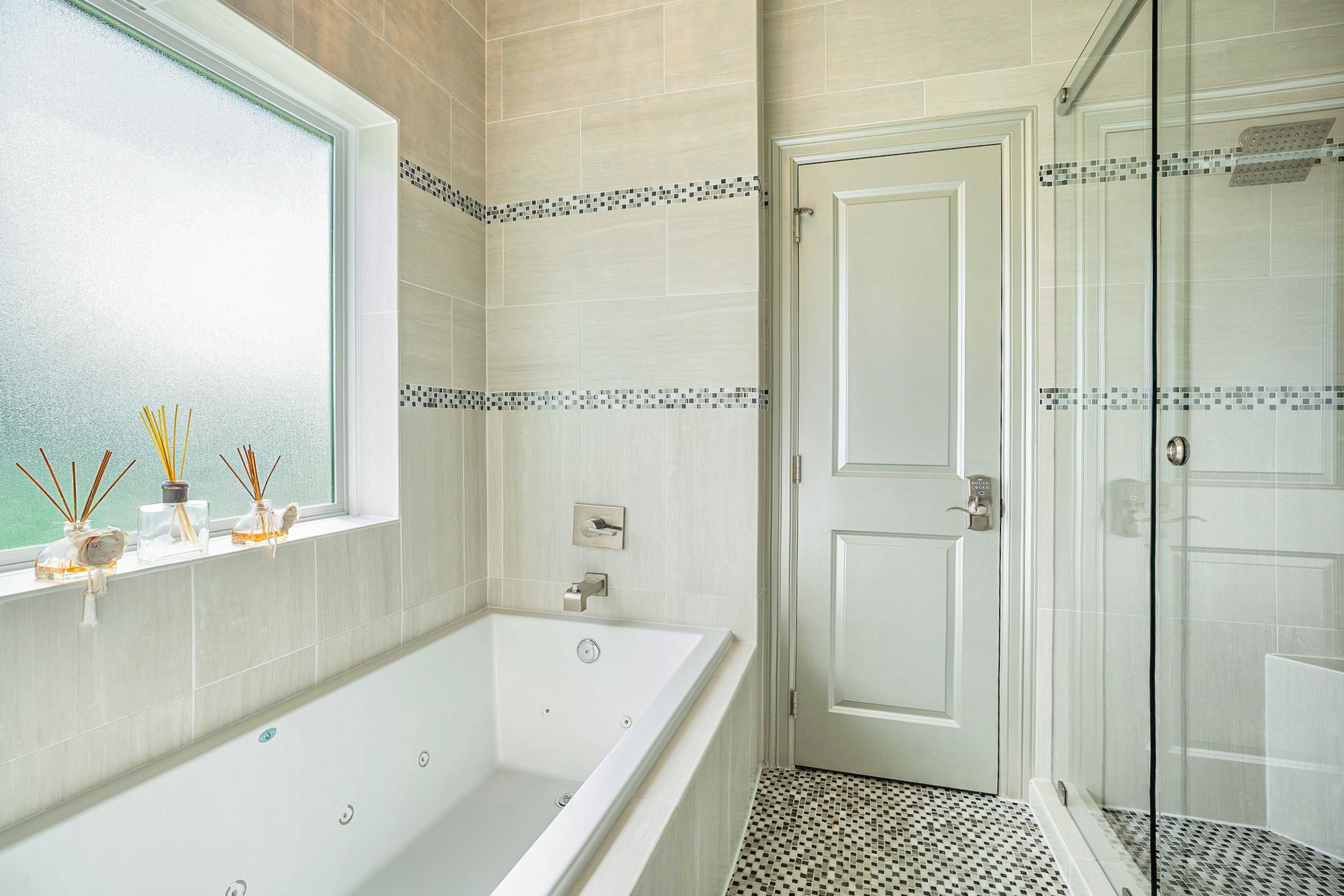Experience luxury in this elegant bathroom featuring a spacious soaking tub, sleek glass-enclosed shower, and stylish tile accents.