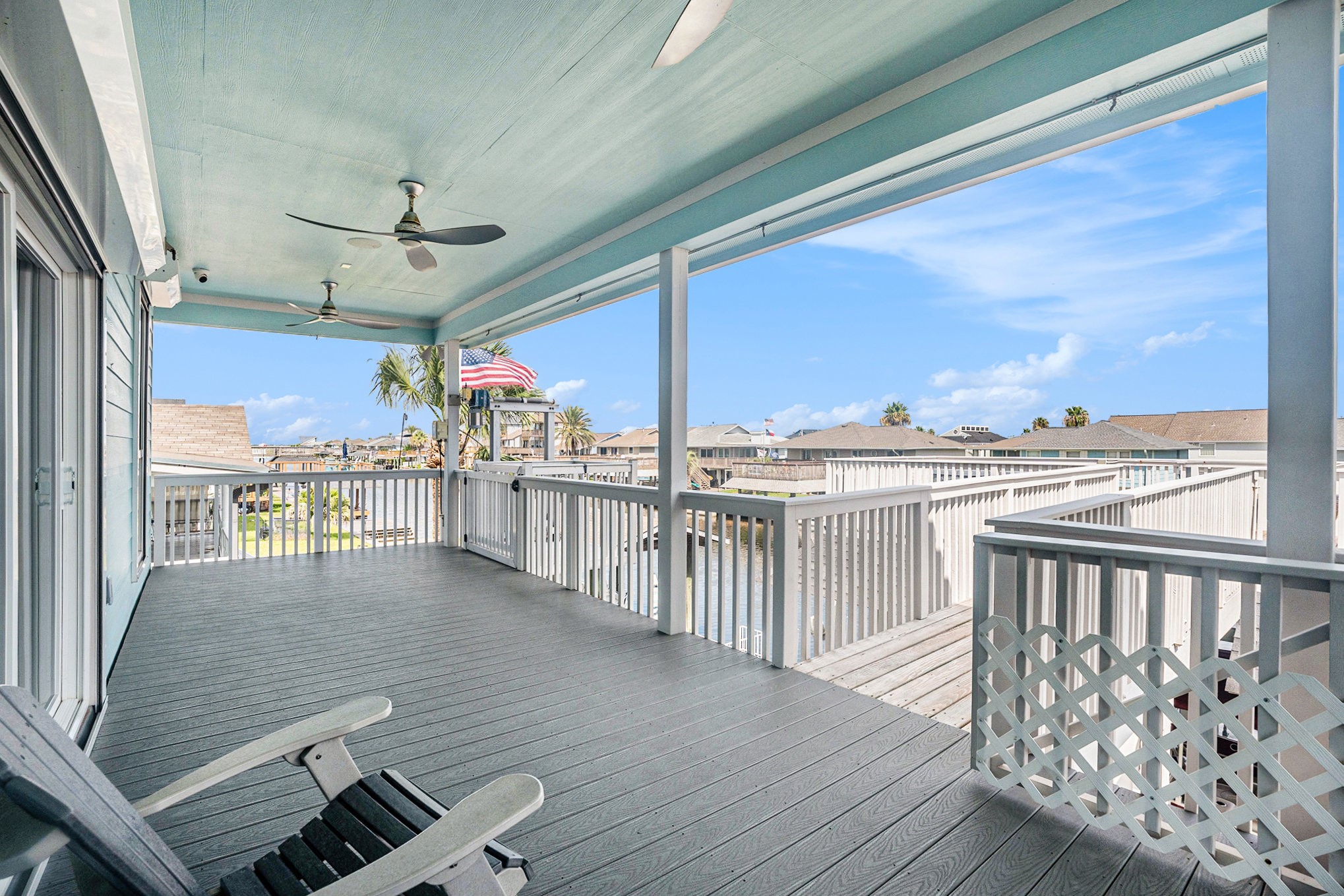 Spacious covered deck with ceiling fans, offering serene views of the surrounding neighborhood and canal. Perfect for relaxing and enjoying the coastal breeze.
