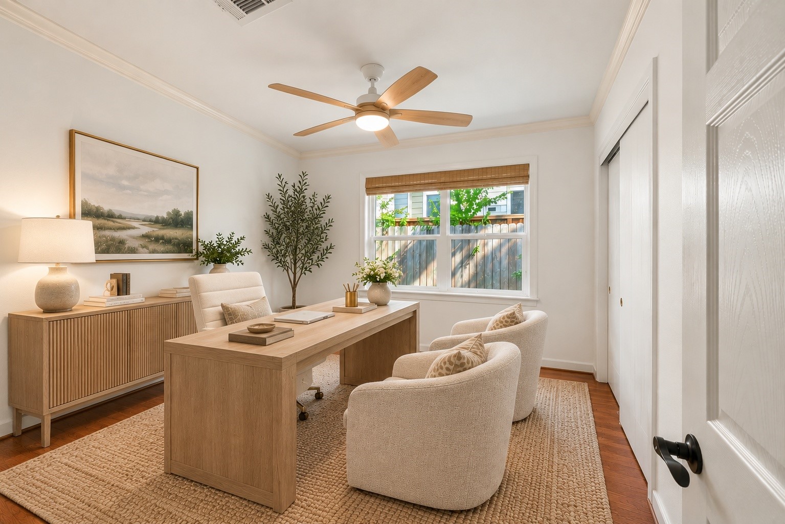 Bright and inviting home office featuring a large window, neutral decor, and elegant furnishings, perfect for a productive work environment. Virtually staged