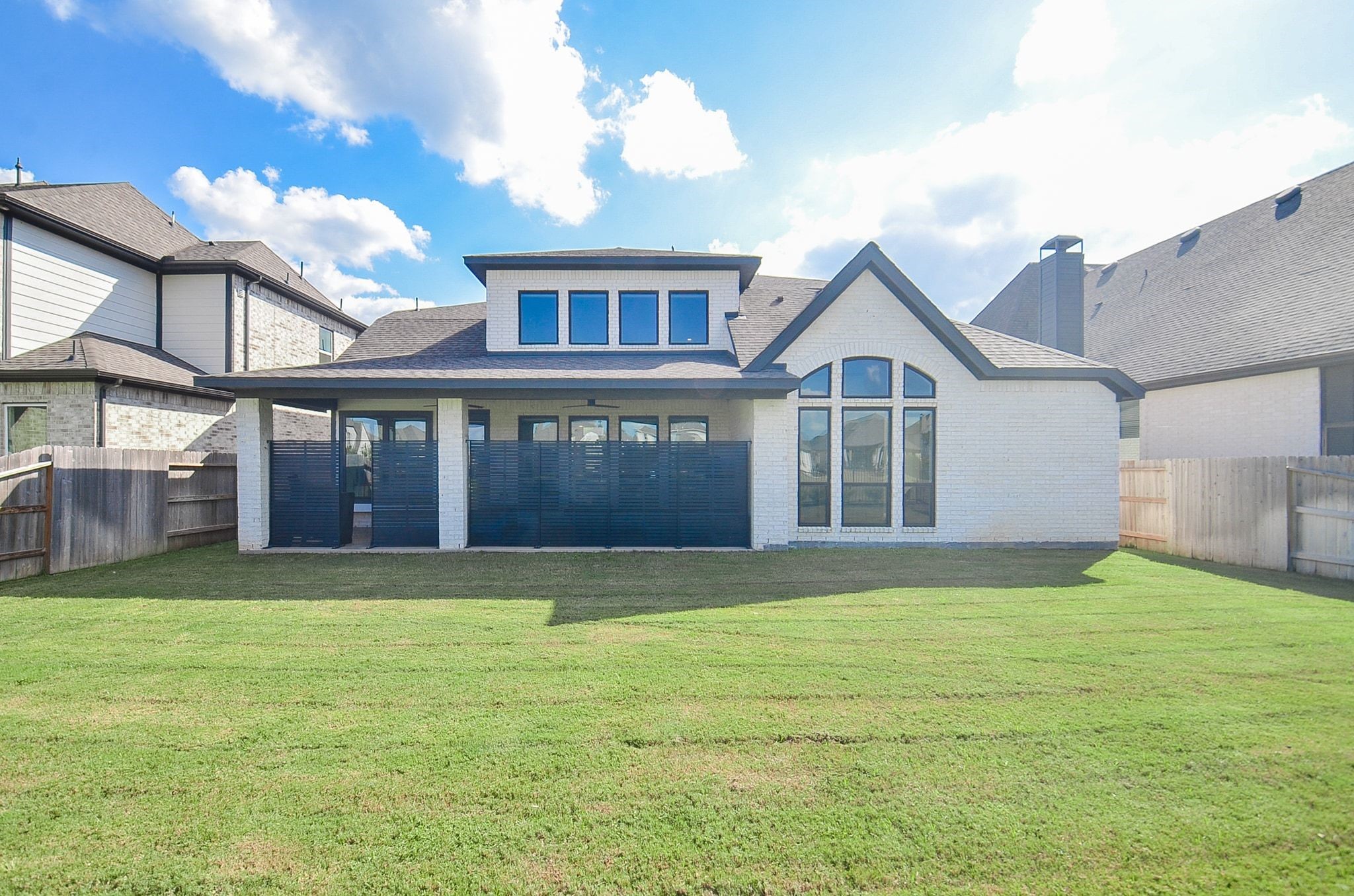 Stunning rear elevation showcasing distinctive architecture, oversized windows, and covered patio.