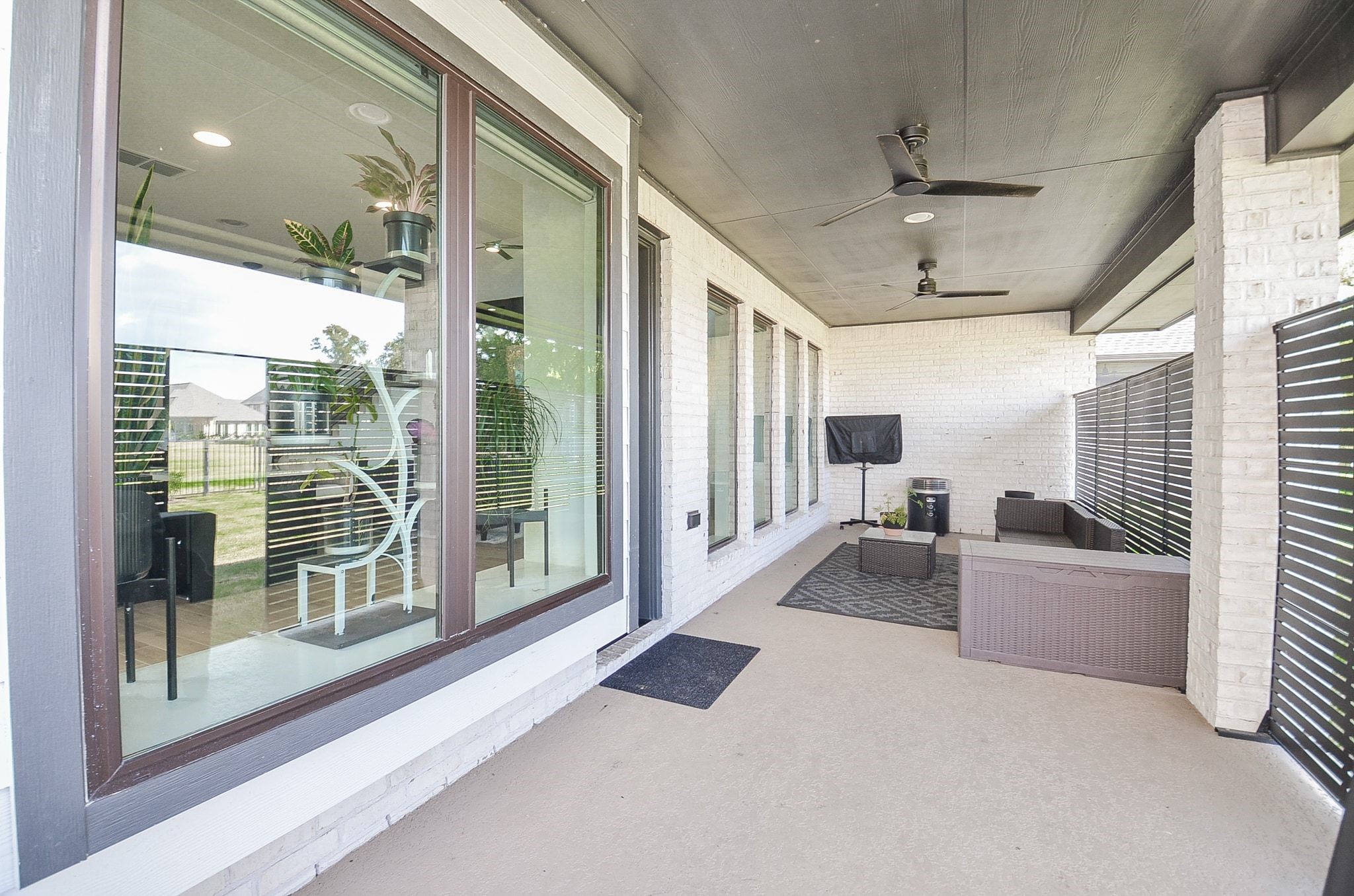 Extended covered patio featuring ceiling fans, privacy screens, and inviting outdoor seating.