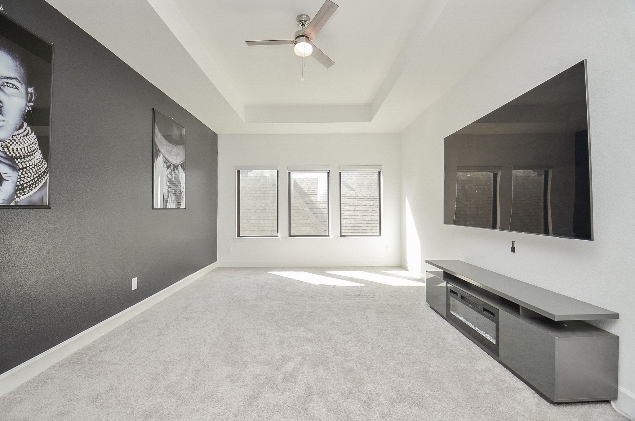 Versatile upstairs media room with tray ceiling and stylish accent wall. TV is not included.