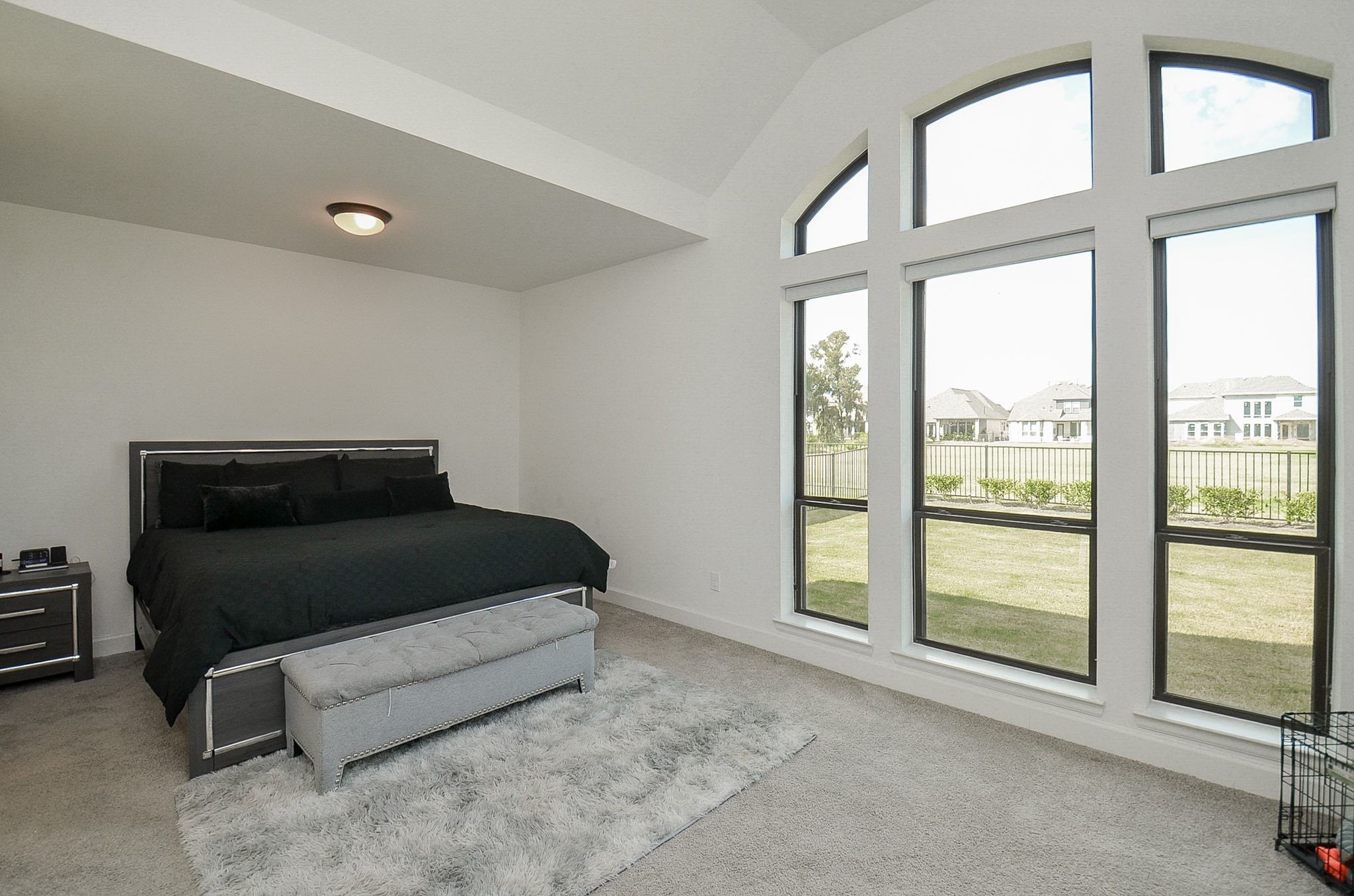 Spacious primary suite featuring soaring ceilings, electric blinds, dramatic windows, and beautiful green-space views.