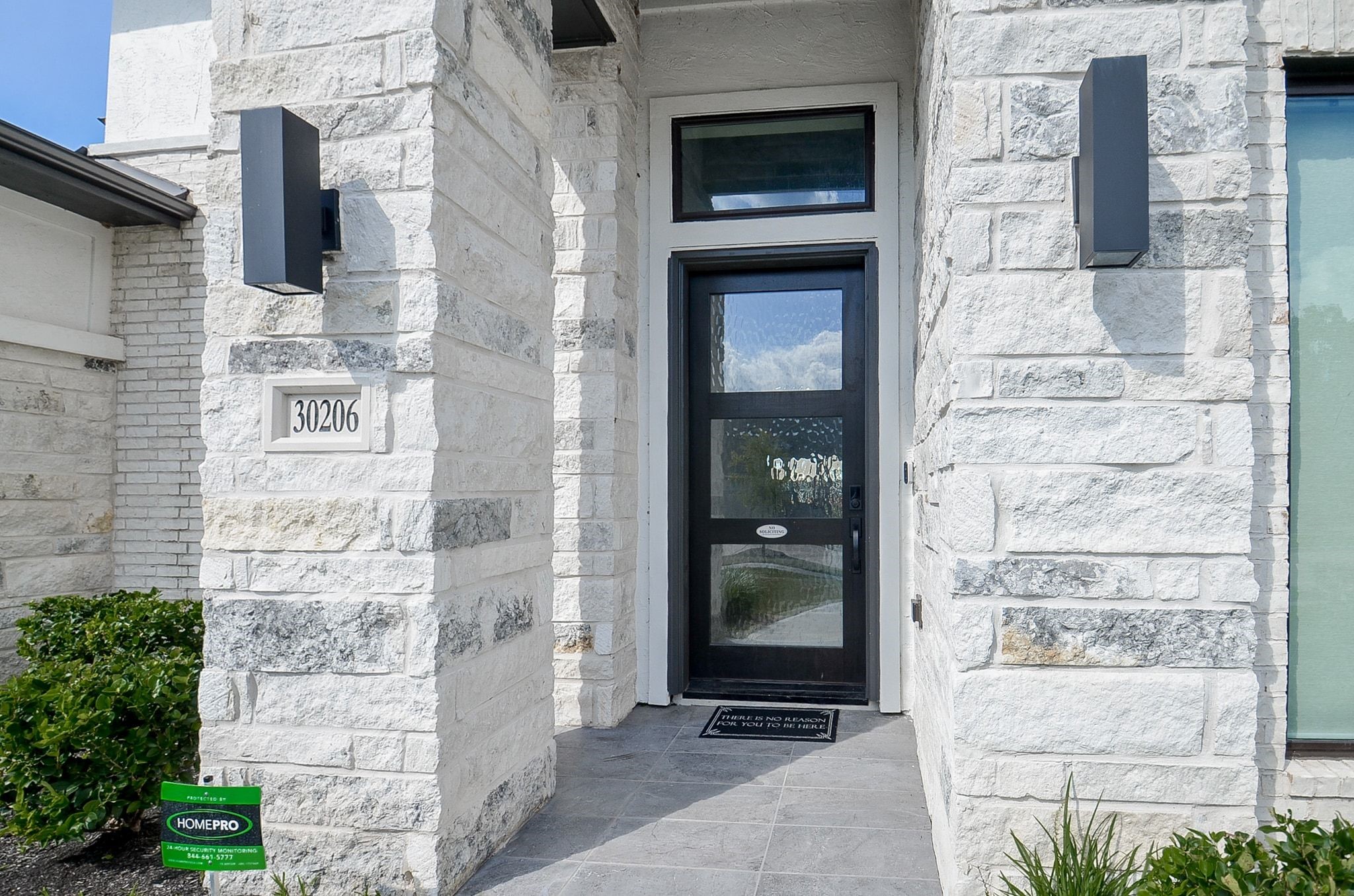 Entrance framed by gorgeous stone columns and a sleek glass door. Entrance framed by gorgeous stone columns and a sleek glass door.