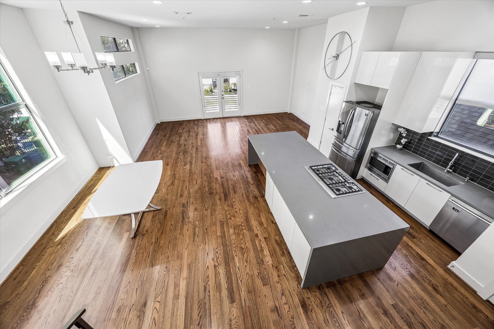 Elevated view showcasing the spacious main living level, with an open kitchen, dining area, and living space. Large windows and balcony doors bring natural light into the interior.