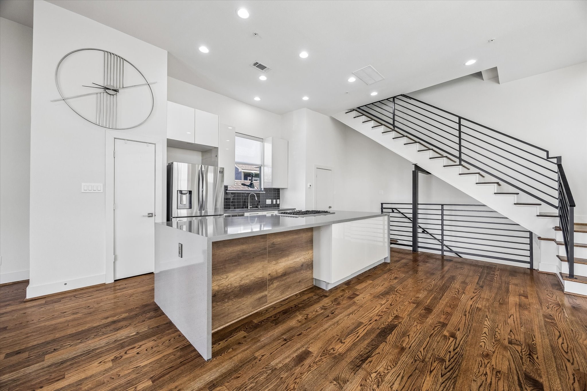 Expansive kitchen island features waterfall edges, integrated cabinetry, and generous counter space. White cabinets and stainless steel appliances complement the kitchens contemporary design. Expansive kitchen island features waterfall edges, integrated cabinetry, and generous counter space. White cabinets and stainless steel appliances complement the kitchens contemporary design.