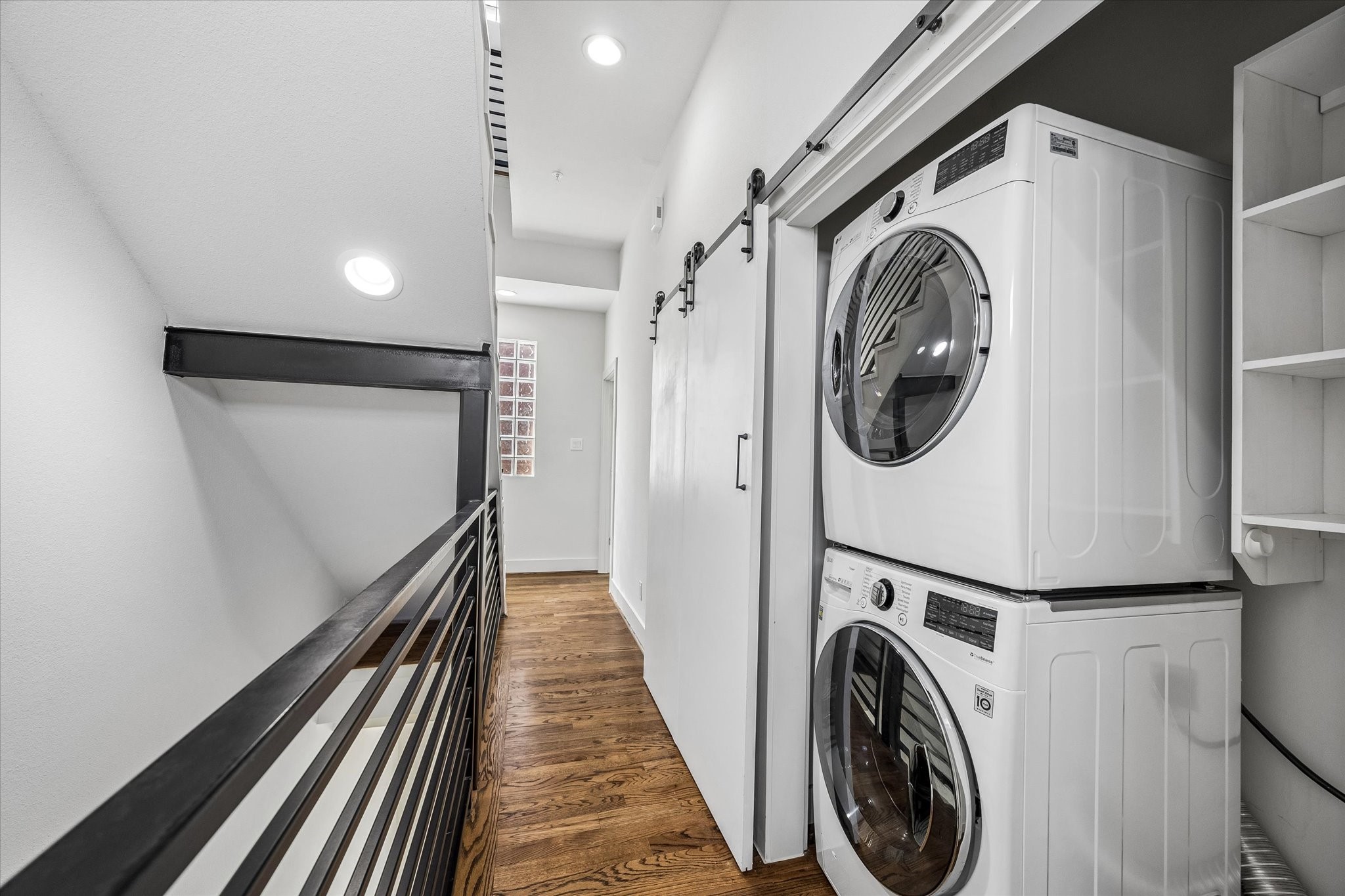 Laundry closet accommodates a stacked washer and dryer, with built-in shelving for storage. Sliding doors provide convenient access from the hallway.
