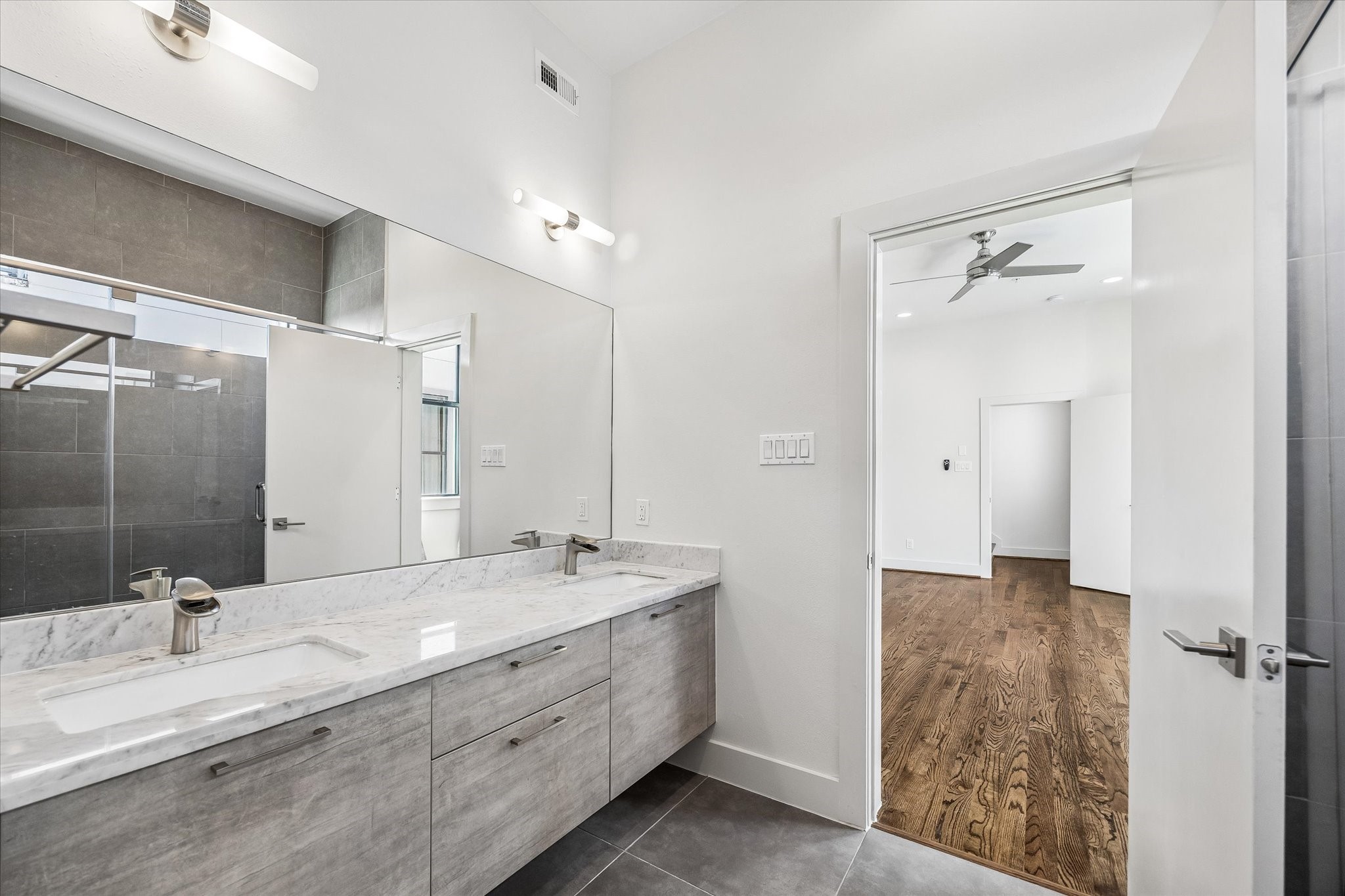 Extended double-sink vanity offers generous counter space and cabinet storage. The bathroom connects directly to the primary bedroom.