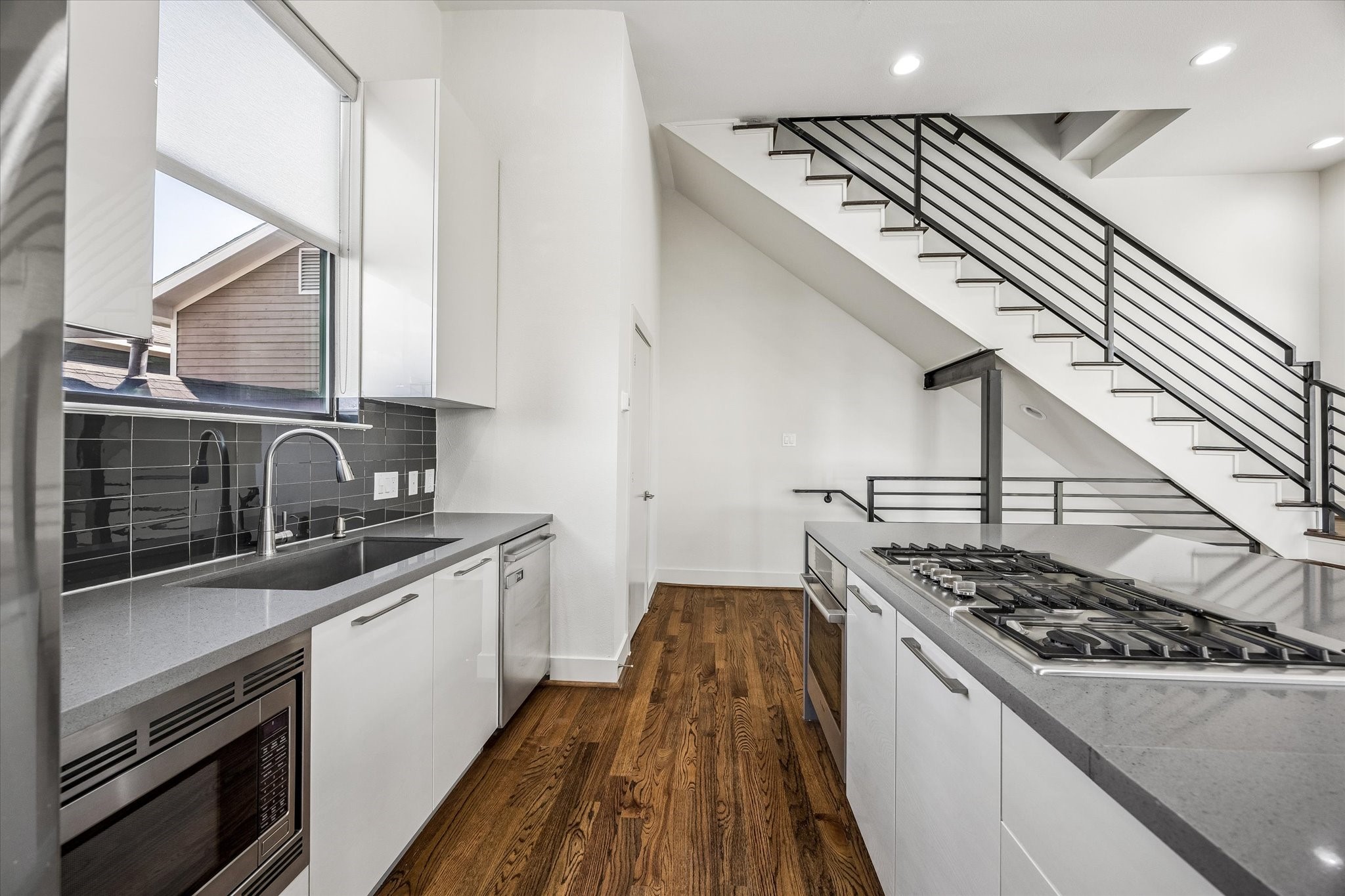 Kitchen features a gas cooktop, built-in oven and microwave, dishwasher, and undermount sink beneath a window. Generous cabinetry and counter space provide practical storage and preparation areas.