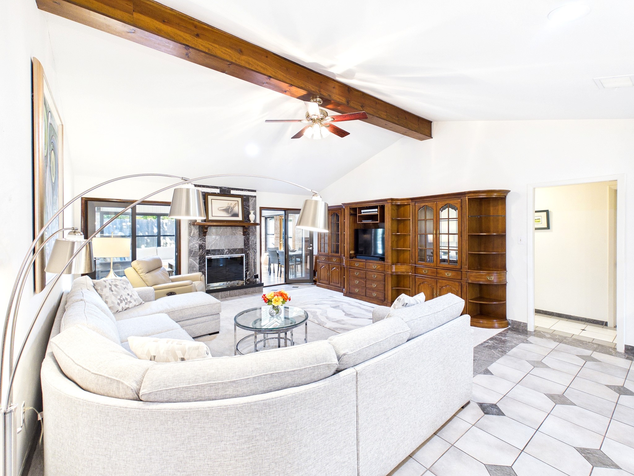 Experience the perfect blend of elegance and comfort in this spacious living area, featuring a cozy fireplace, a stylish sectional, and natural light streaming through expansive windows.