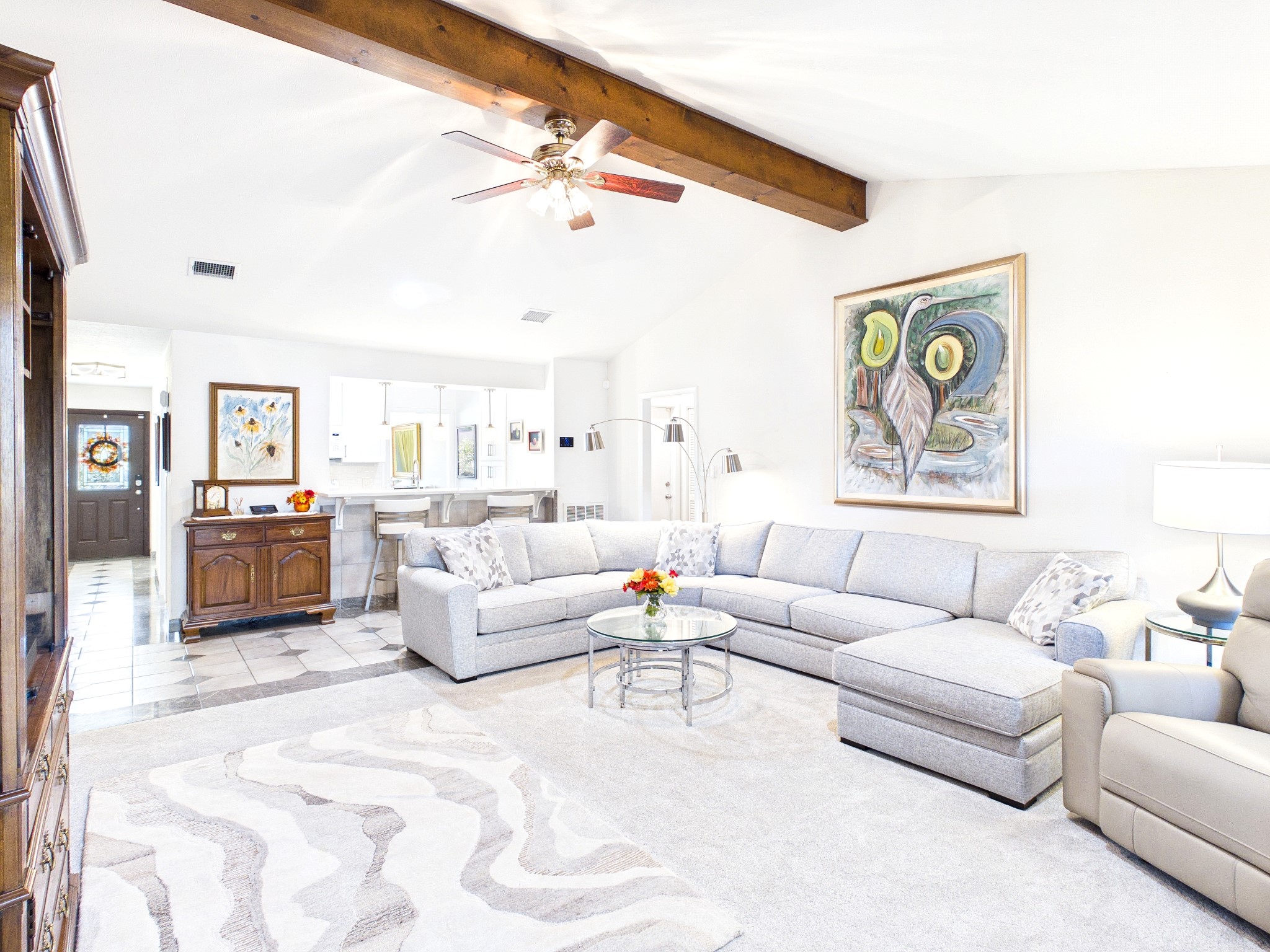 Expansive living area with abundant natural light, featuring a comfortable sectional sofa, elegant decor, and a seamless flow to the kitchen, perfect for relaxation and entertaining.