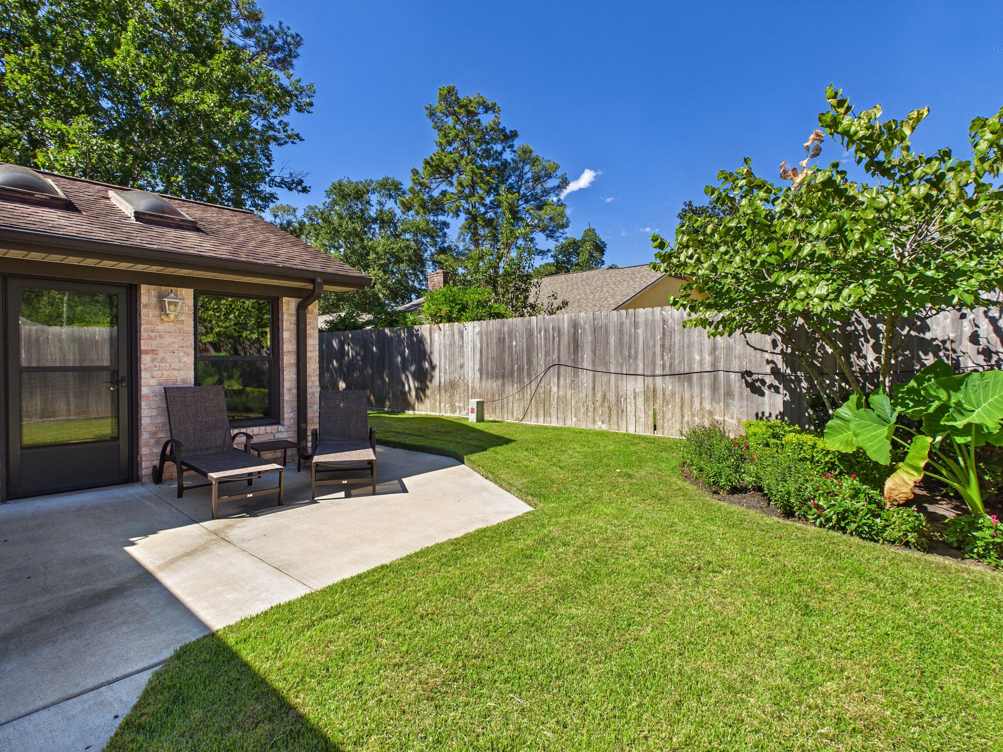 Charming backyard with a cozy patio area, perfect for relaxing, surrounded by lush greenery and privacy fencing.
