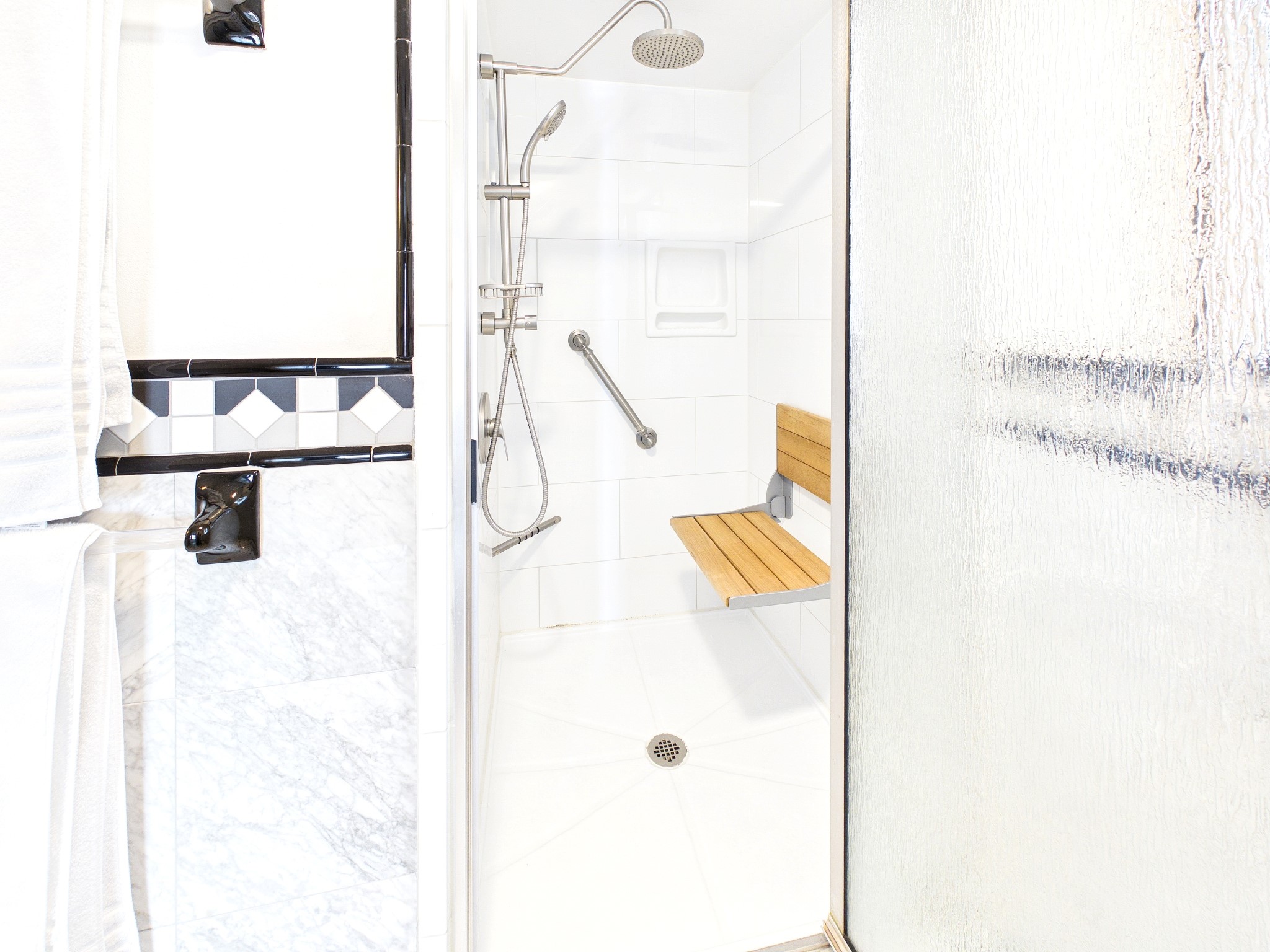 Experience ultimate relaxation in this luxurious bath, featuring sleek fixtures, elegant tilework, and a chic walk-in shower with a convenient fold-down seat.